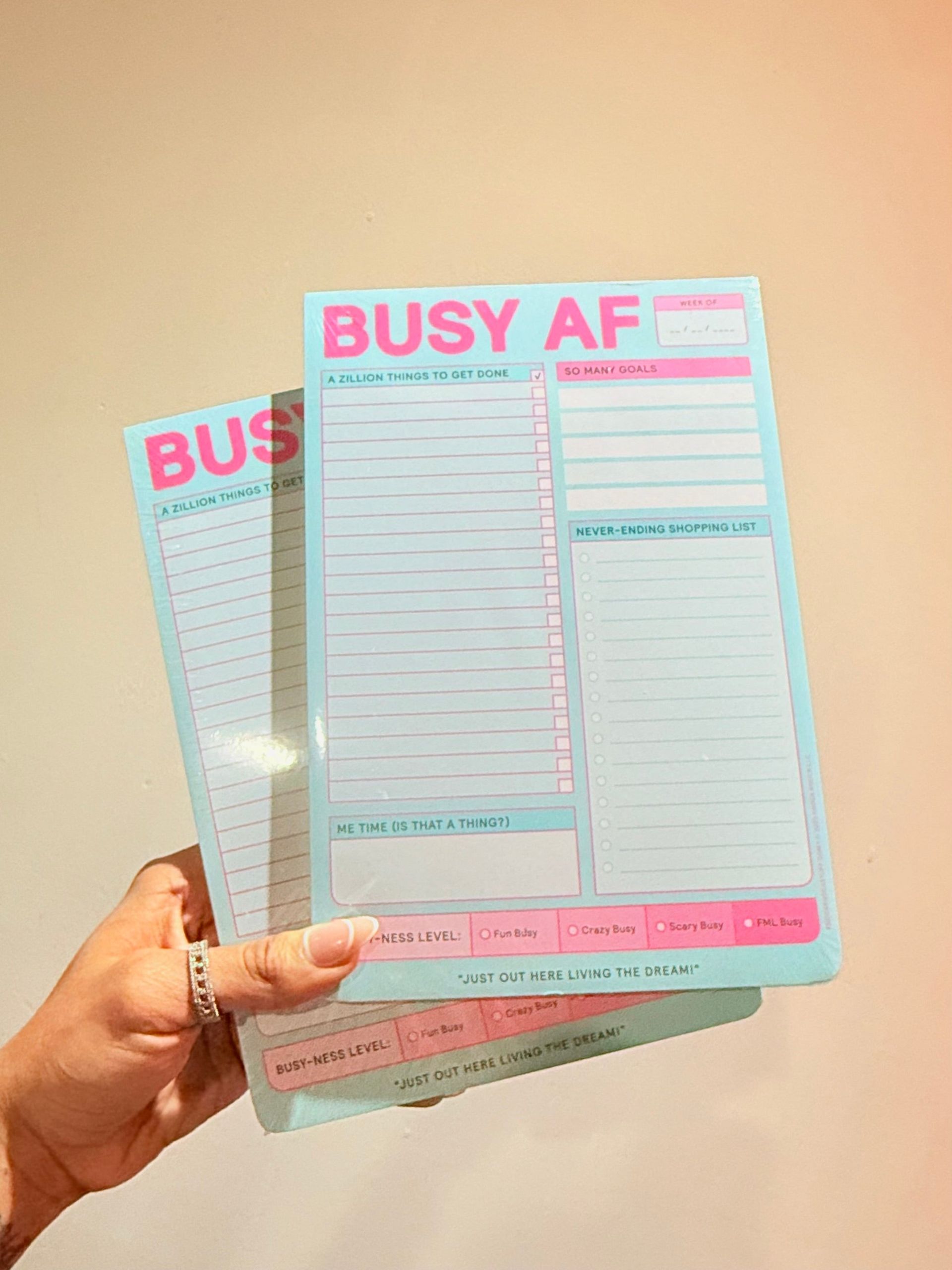 A person is holding a piece of paper that says busy af