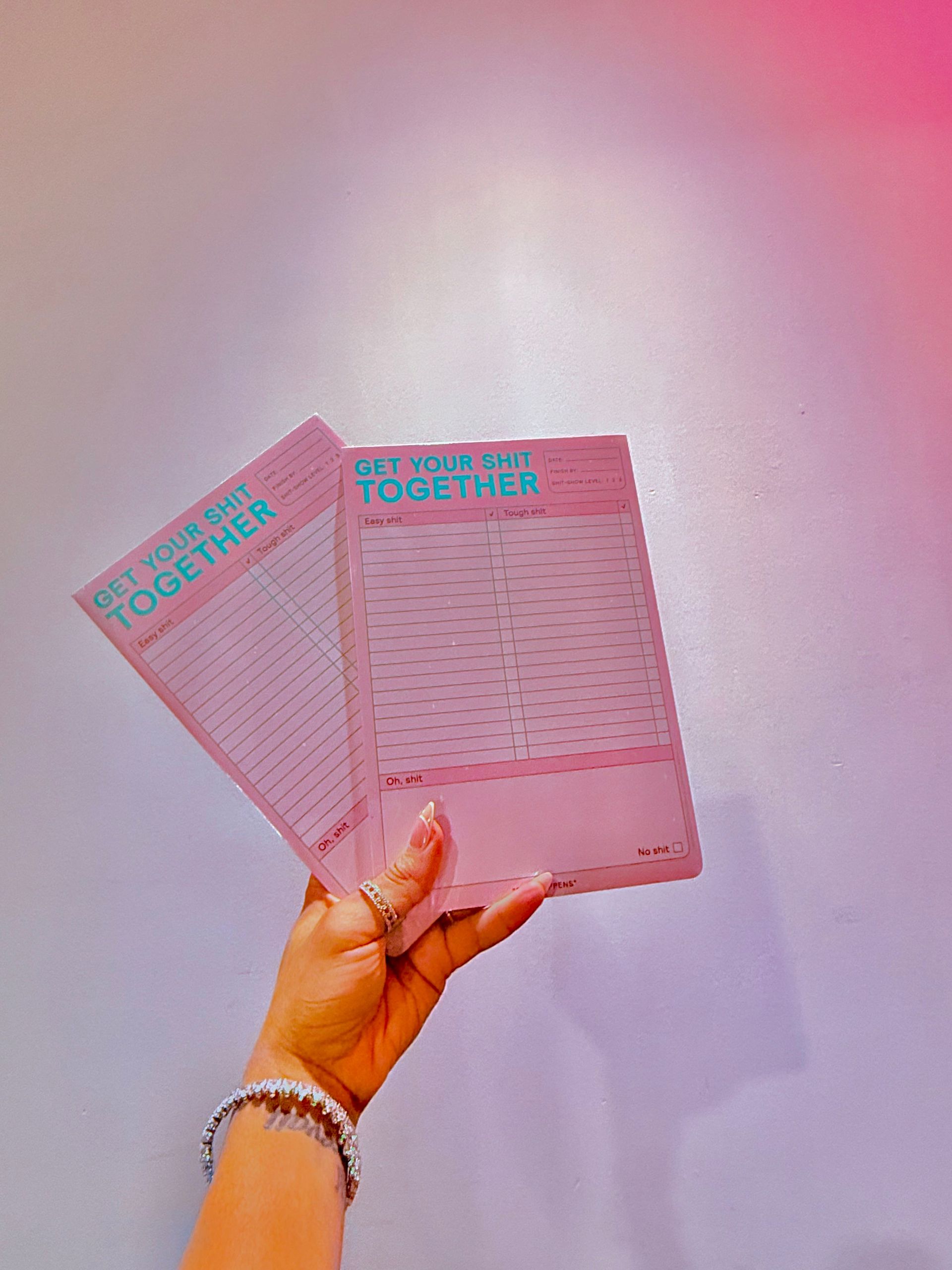 A person is holding two pink papers in their hand.