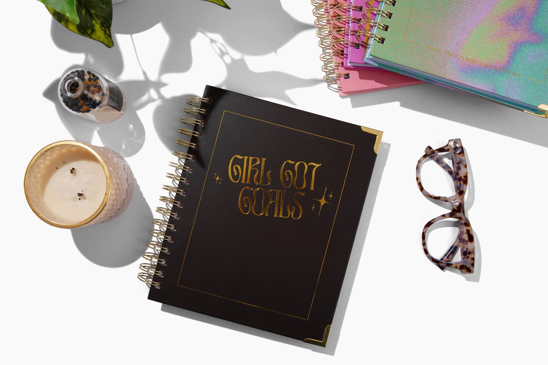 A notebook with the words `` girl got girls '' written on it is sitting on a table next to a candle and glasses.