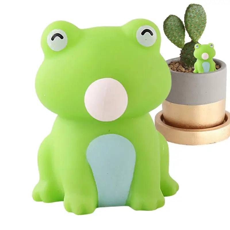 A green frog sitting next to a potted cactus
