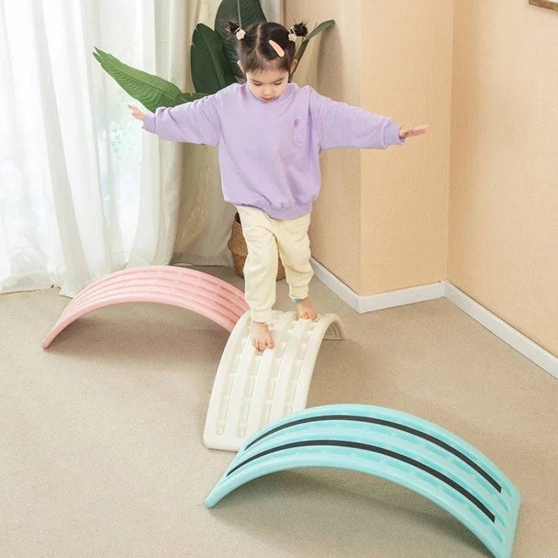 A little girl is standing on a balance board in a room.
