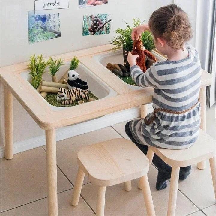 A little girl is sitting at a wooden table playing with toys