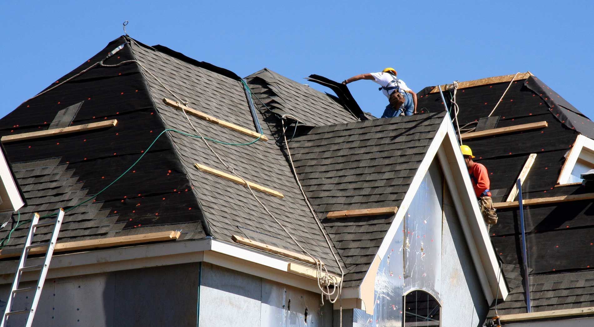 Two men are working on the roof of a house.