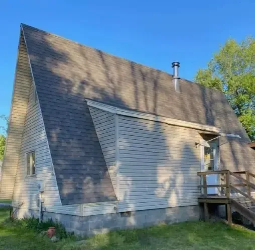 A white house with a gray roof and stairs