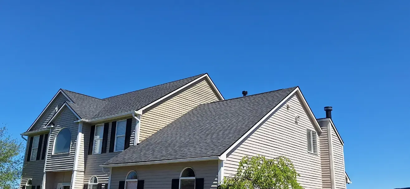 A large house with a gray roof and a blue sky in the background.
