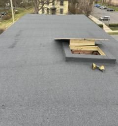 Two men are working on a roof with a drill.