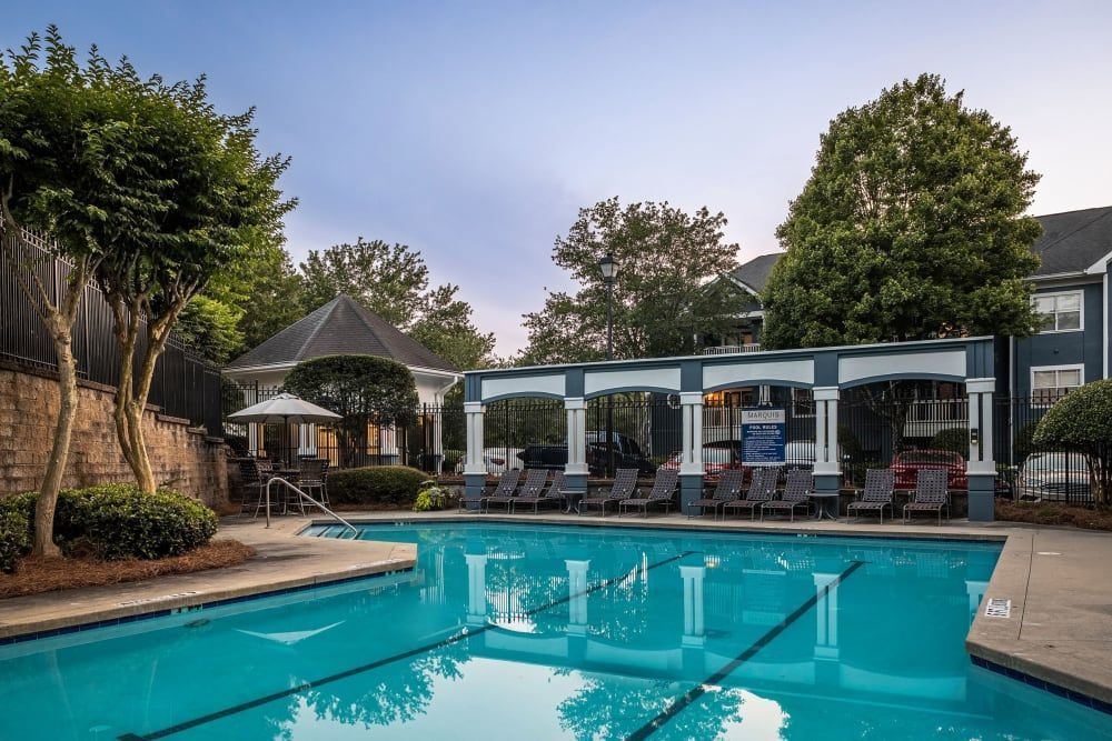 a large swimming pool surrounded by trees and chairs in front of a building at Marquis Midtown West in Atlanta, GA.