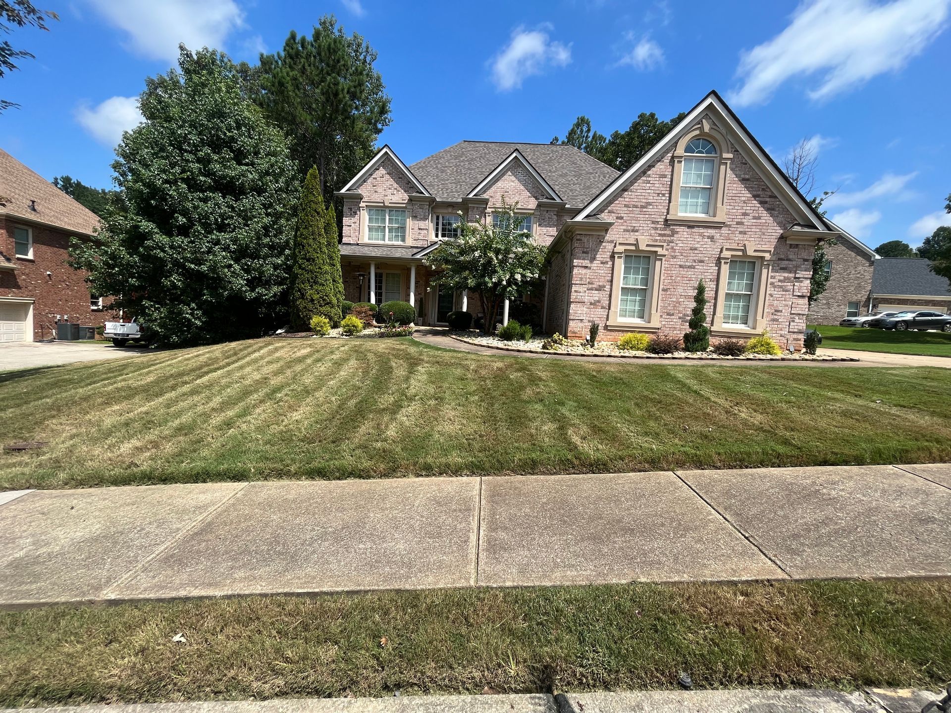 Brick house with manicured lawn and sidewalk on a sunny day.