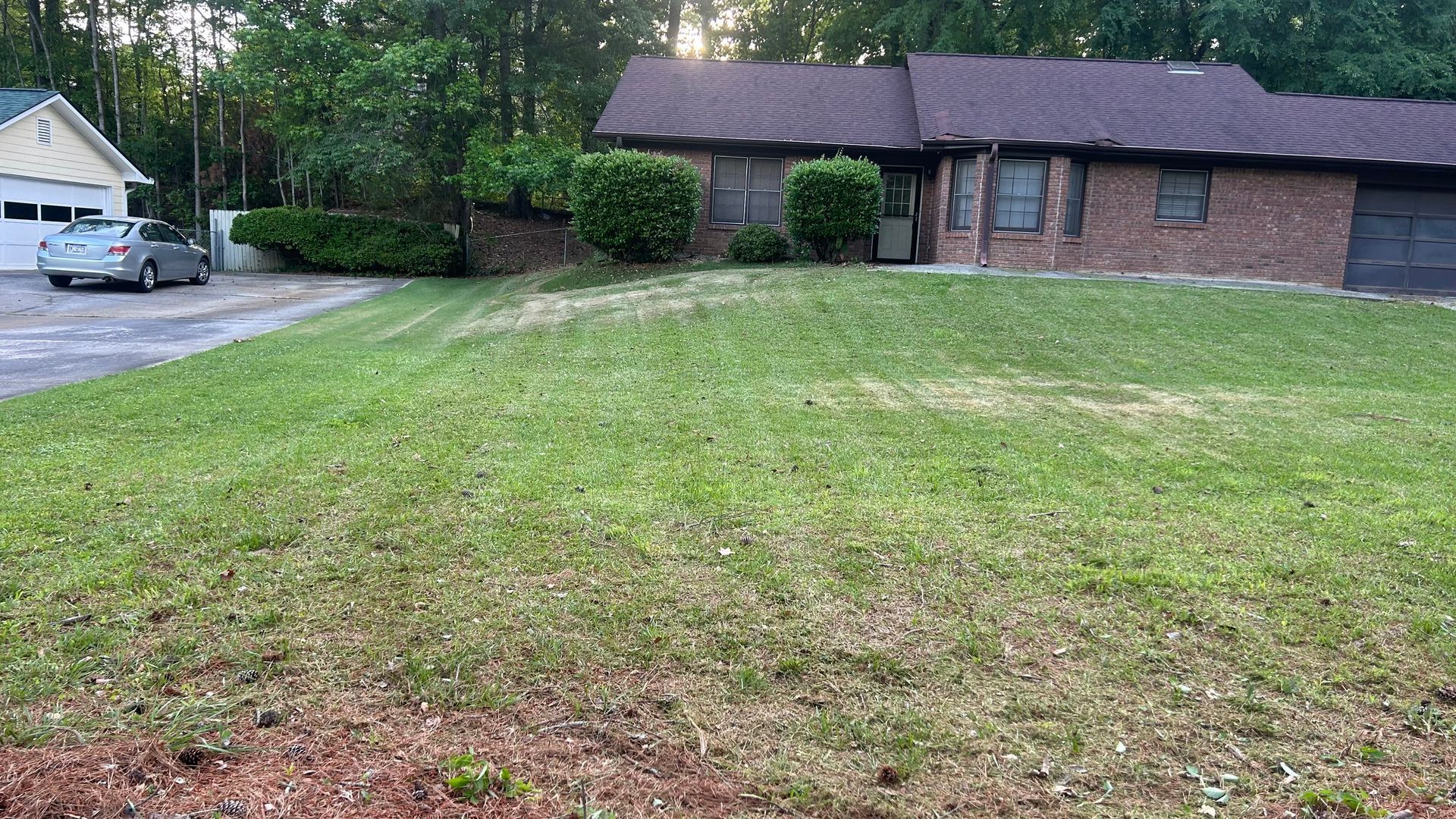 Suburban house with lawn, driveway, detached garage, and a car.
