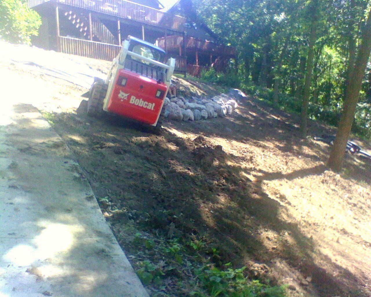 A bobcat tractor is driving down a dirt road