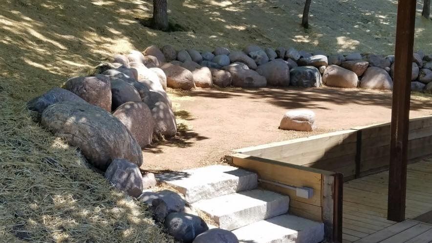 A wooden deck with stairs leading up to a rock wall