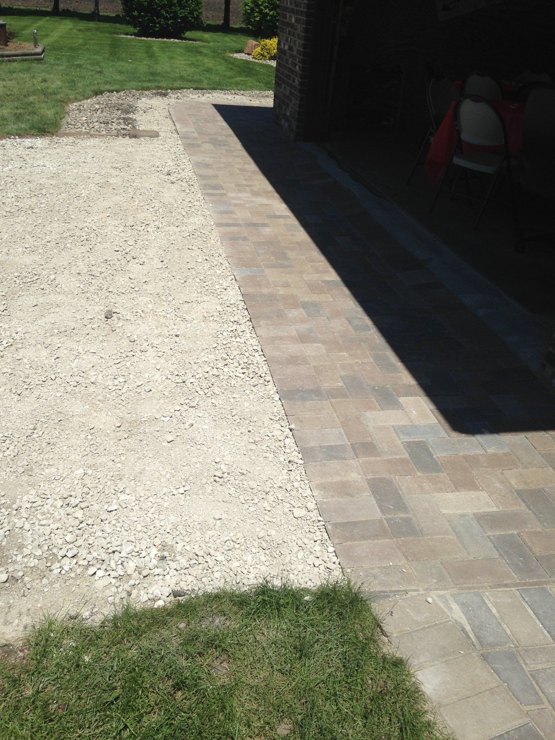 A car is parked in a driveway next to a brick walkway.