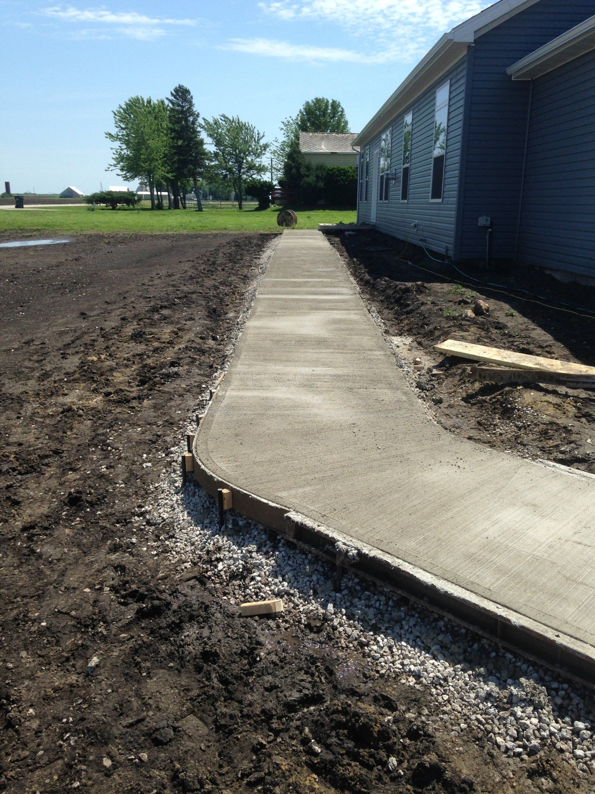 A concrete walkway is being built in front of a house