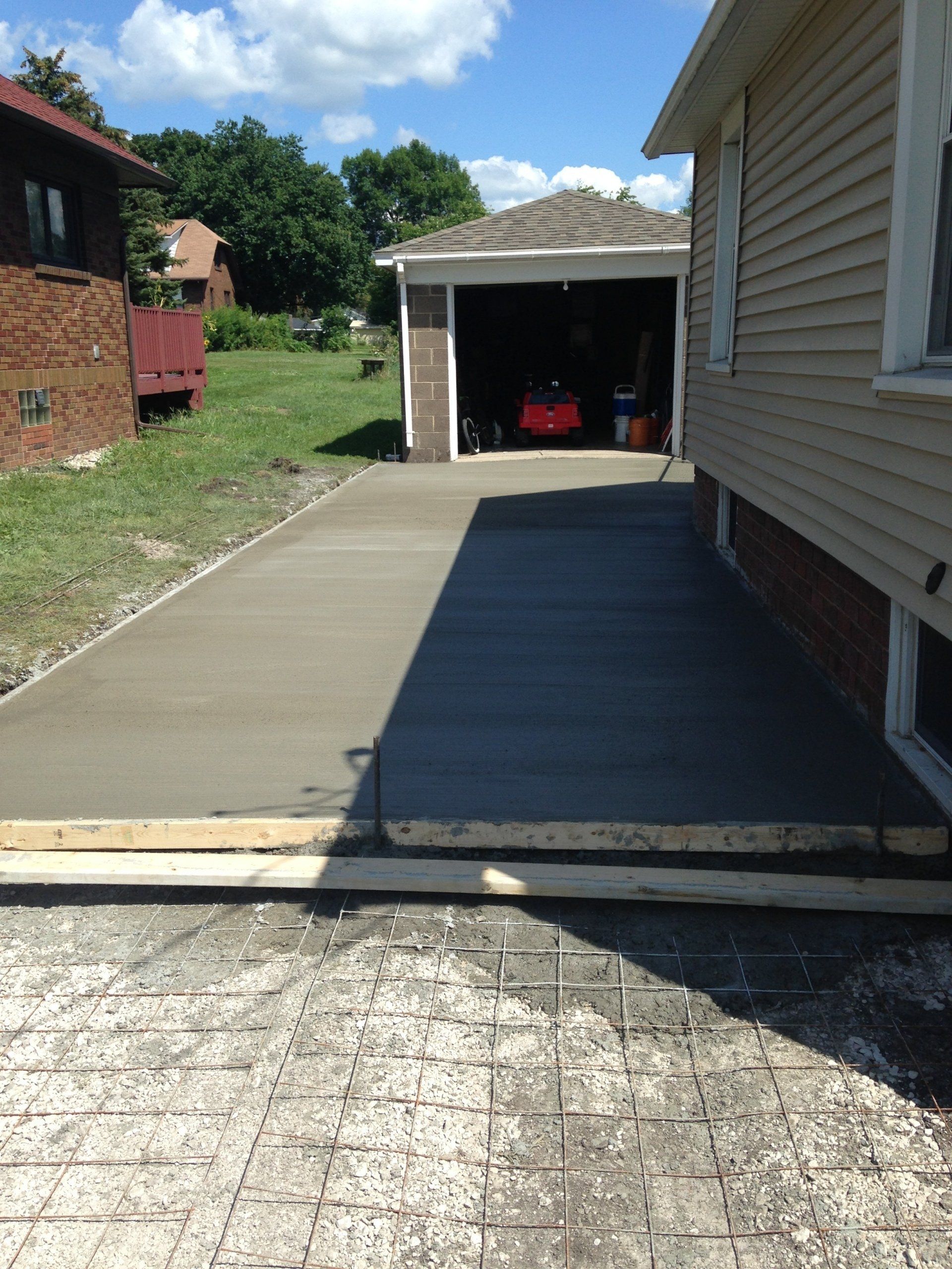 A concrete driveway is being built in front of a house