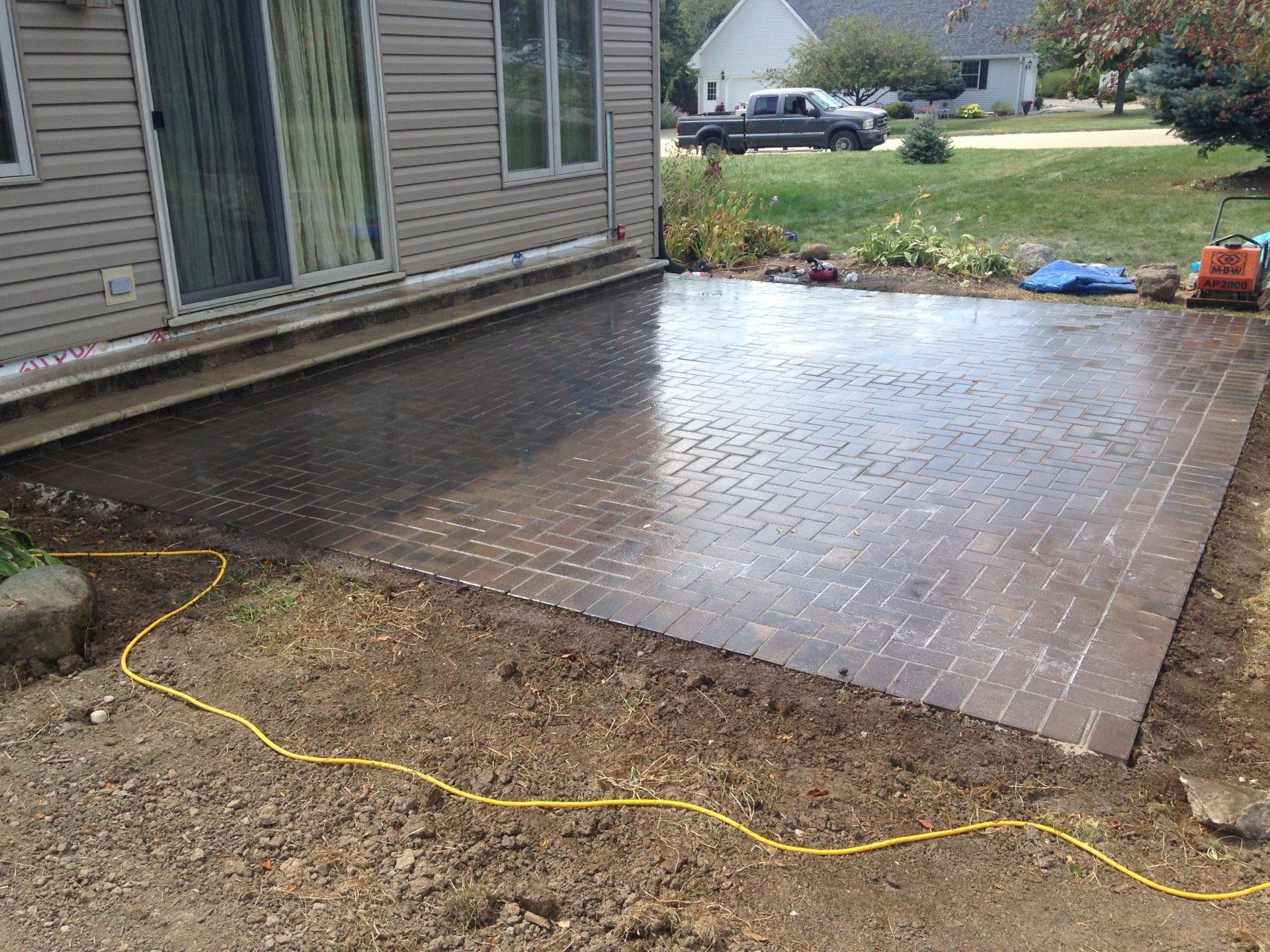 A brick patio is being built in front of a house.