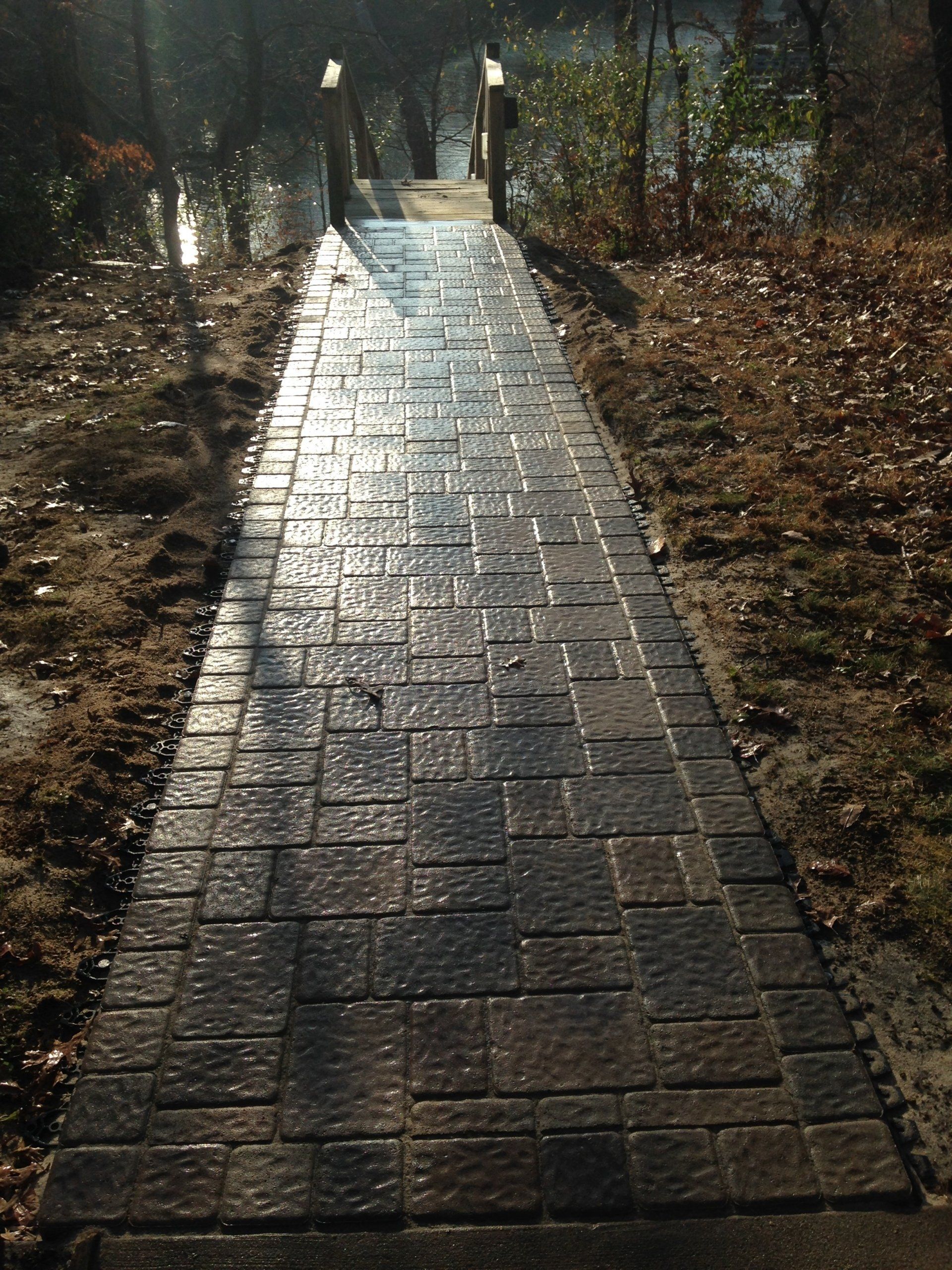 A brick walkway leading to a bridge in the woods