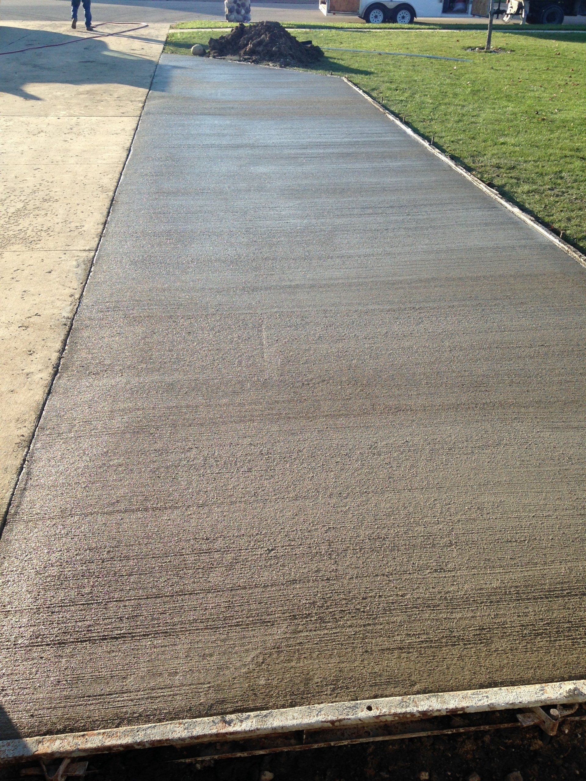 A concrete walkway is being built next to a grassy field.