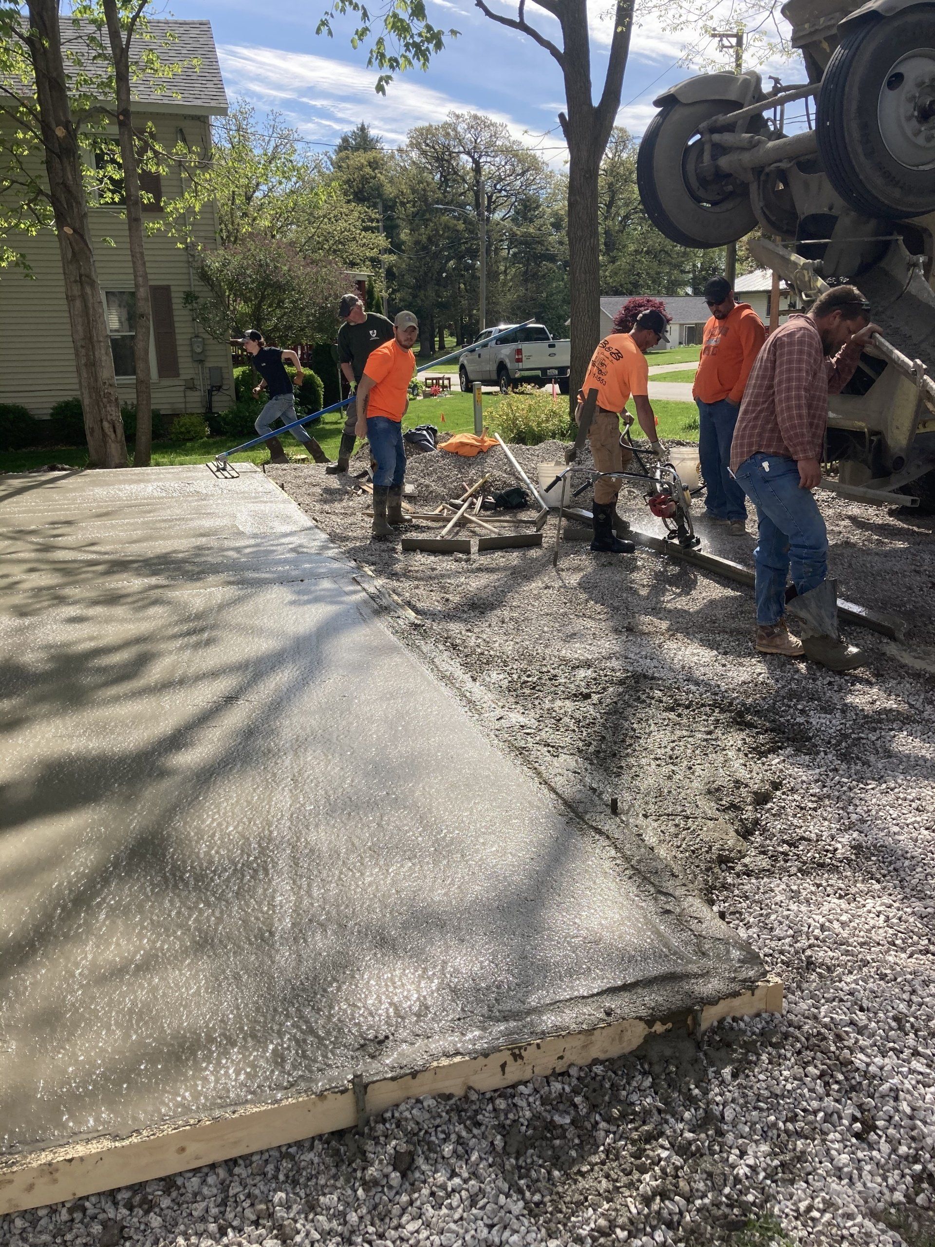 A group of construction workers are working on a concrete driveway.