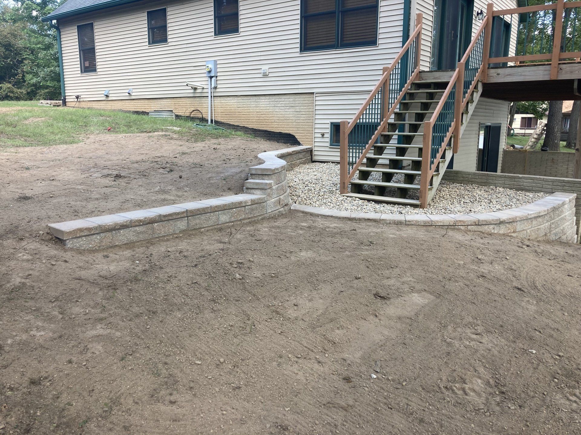 A house with stairs leading up to it is sitting on top of a dirt field.