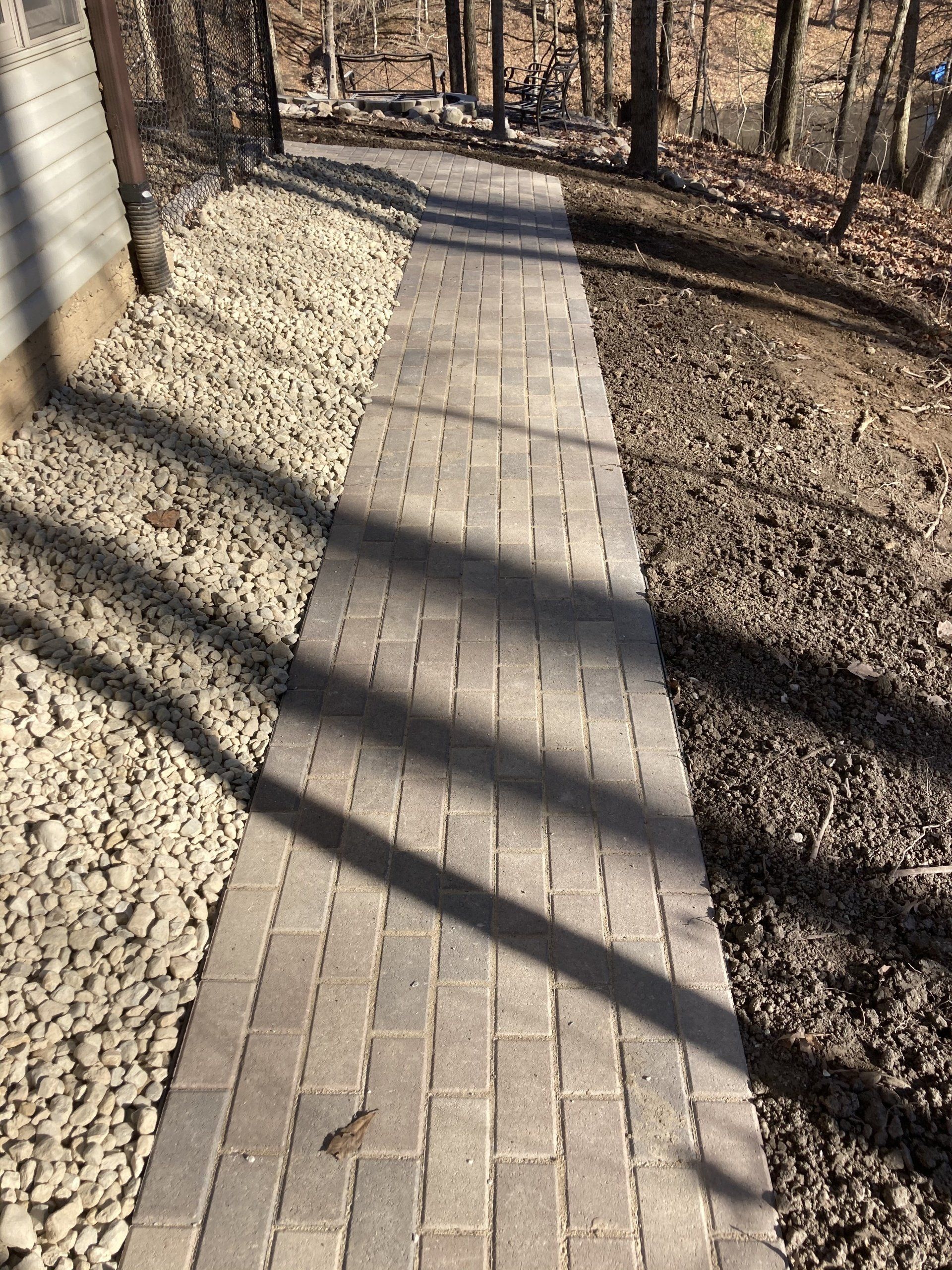 A brick walkway leading to a house in the woods.