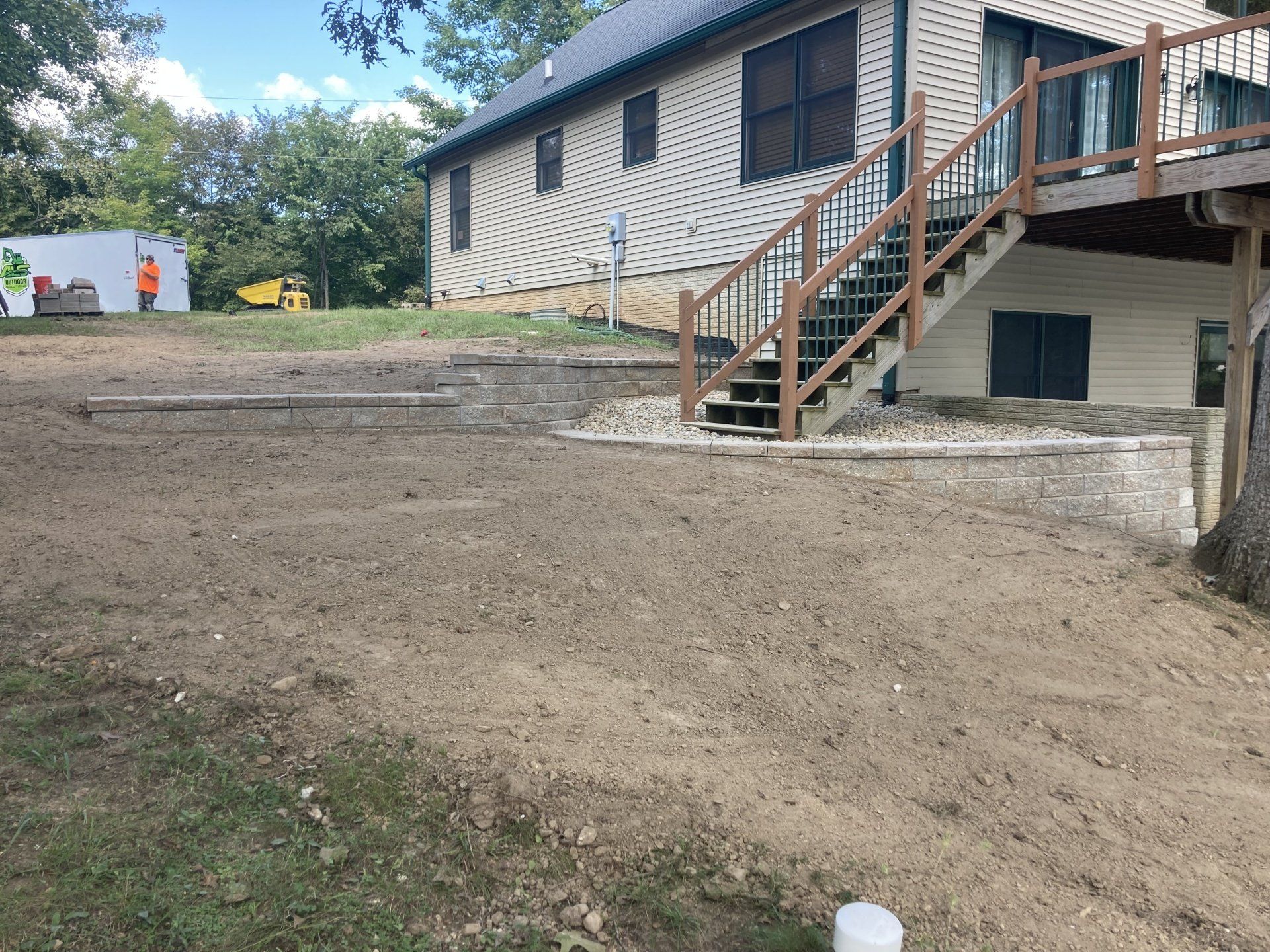 The backyard of a house with stairs leading up to the deck.