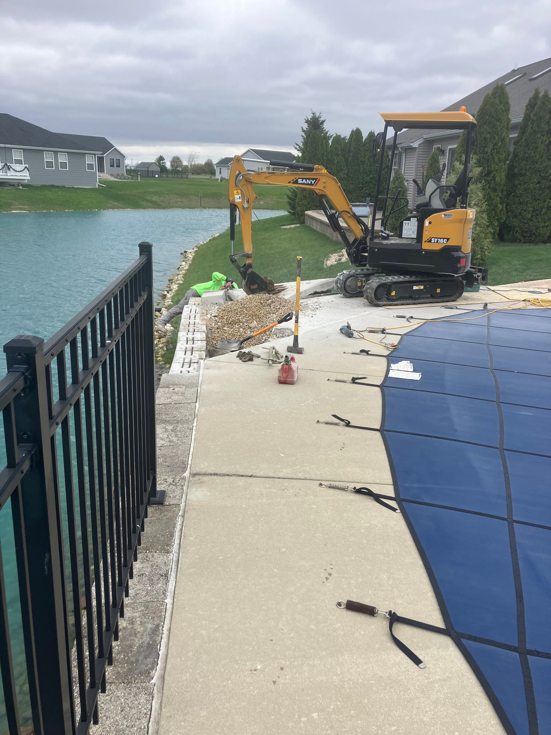 A brick wall is being repaired by a pool.