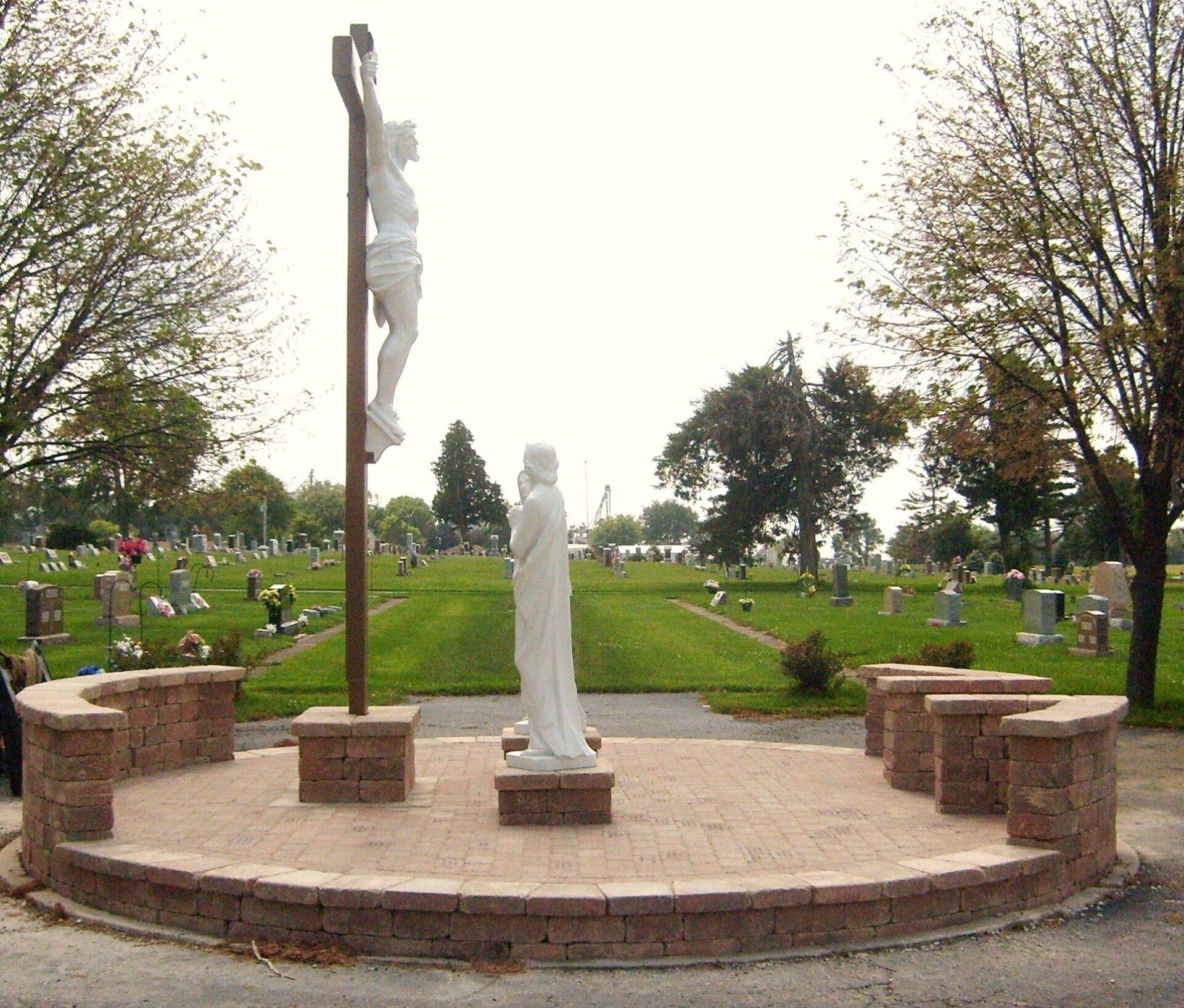 A statue of jesus on a cross in a cemetery