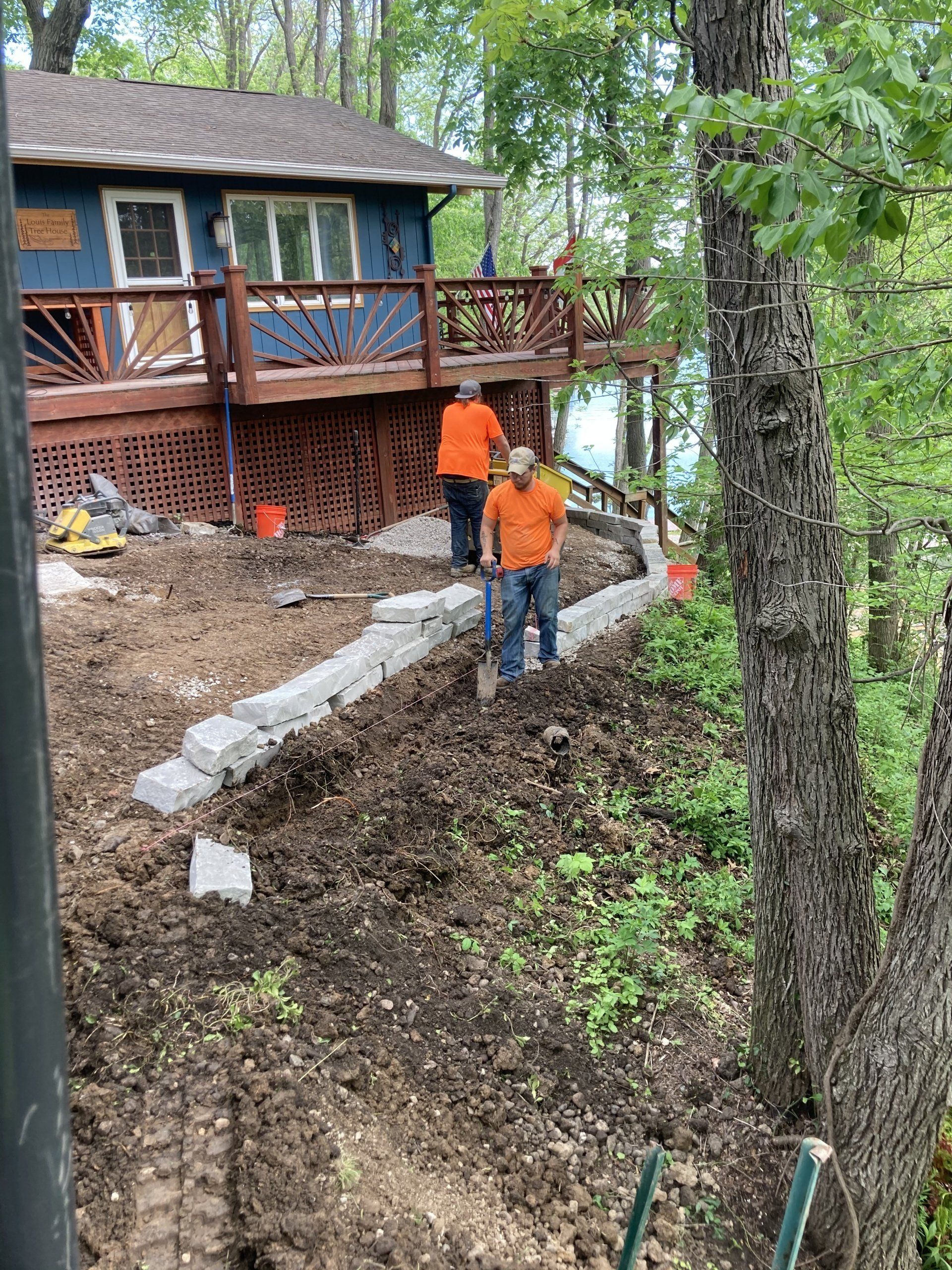 A group of men are working on a retaining wall in front of a house.