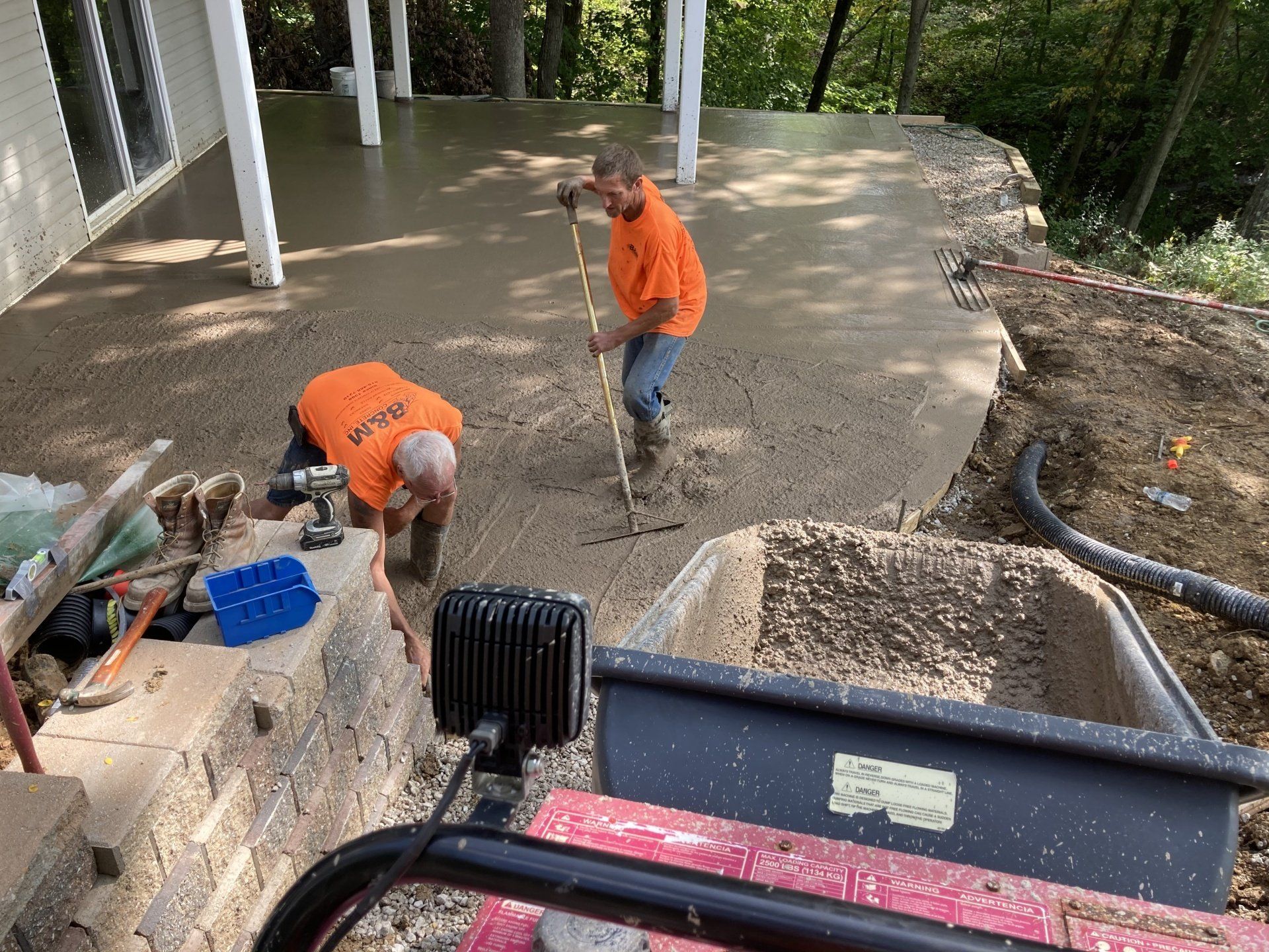 Two men are working on a concrete patio.
