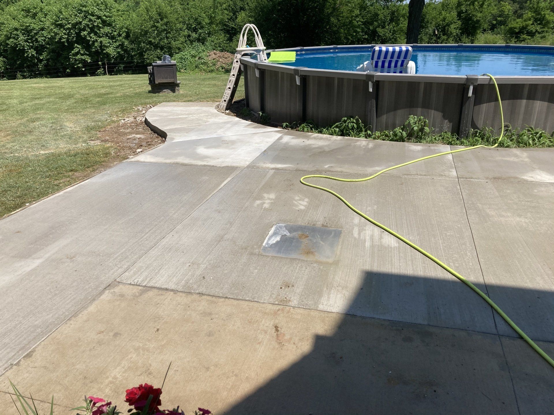 A hose is connected to a concrete patio next to a pool.