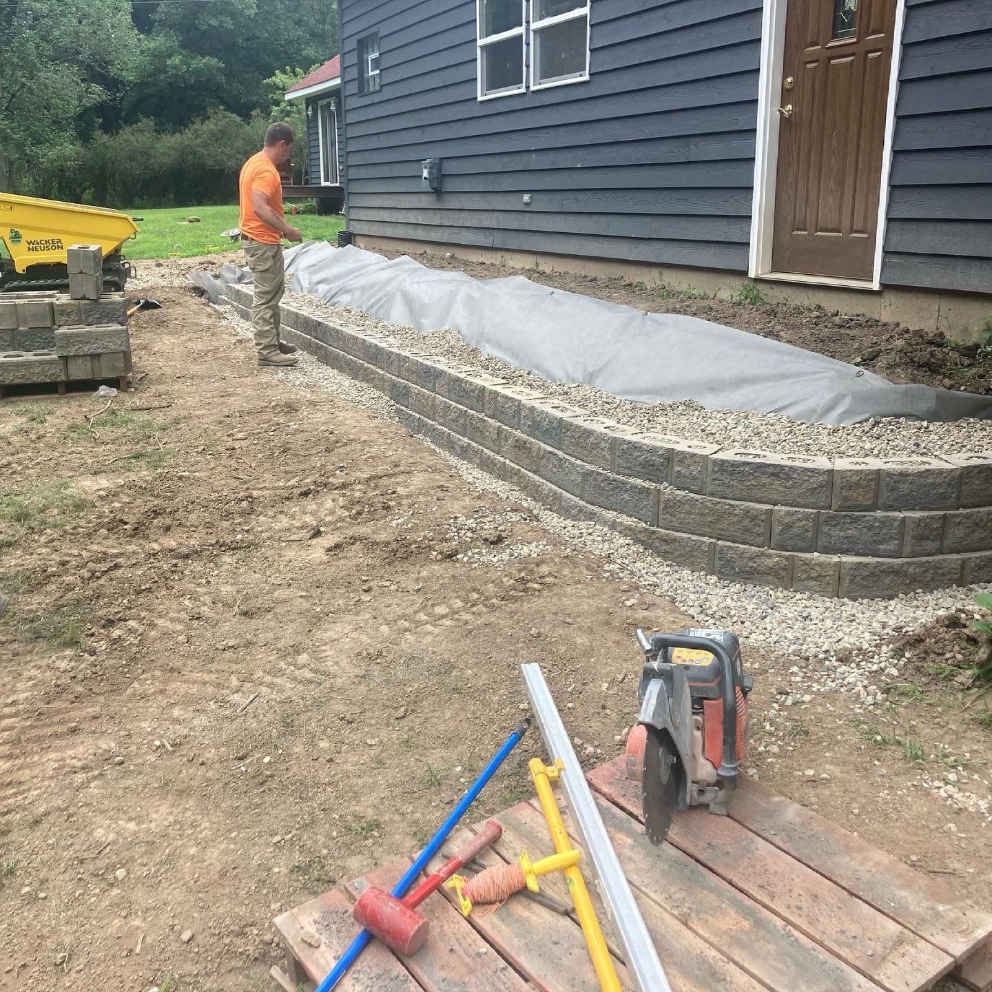 A man is working on a sidewalk in front of a house.