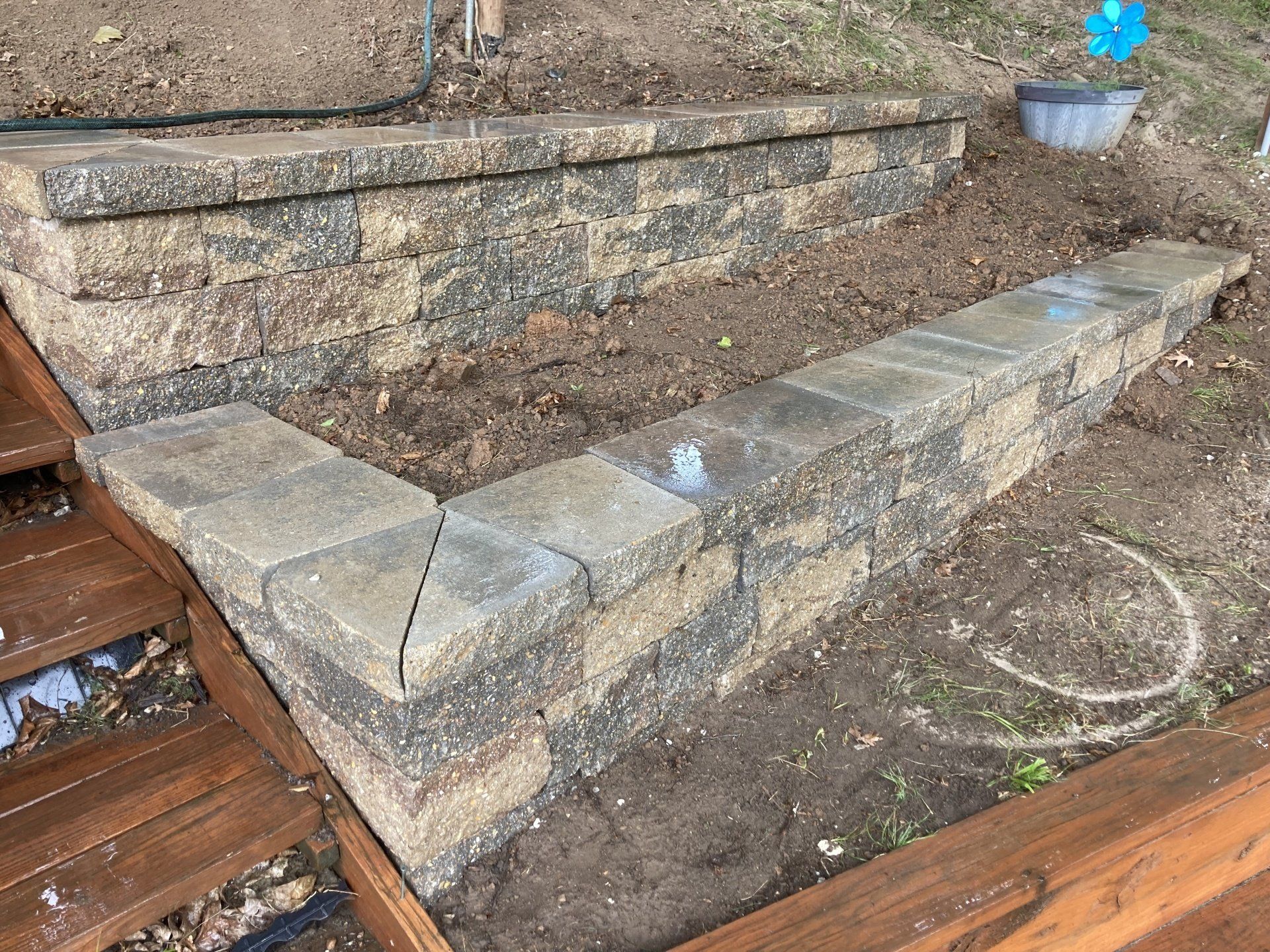 A stone wall is being built next to a wooden deck.