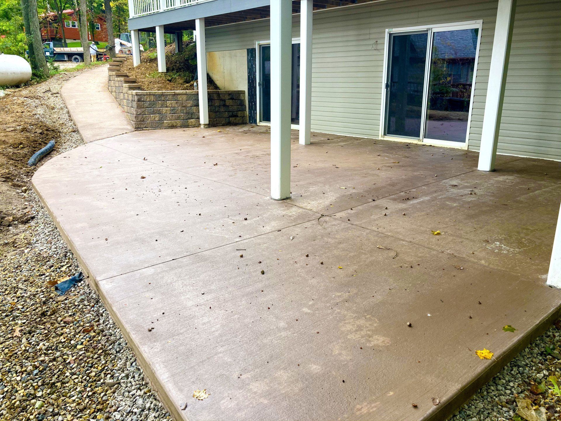 A concrete patio in front of a house with a sliding glass door.