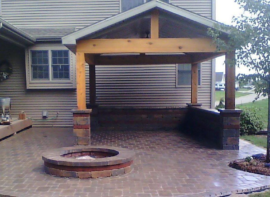 A fire pit in front of a house with a pavilion