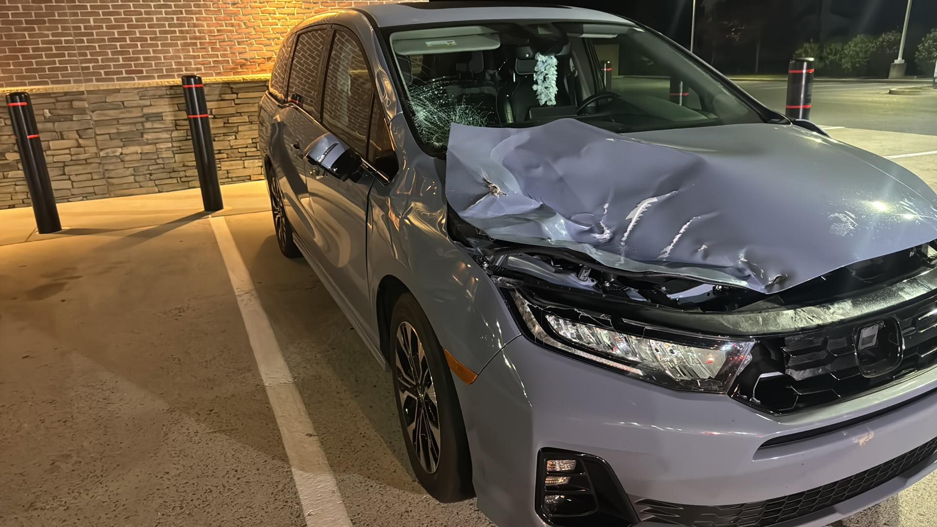Gray SUV with significant front-end damage parked at night near a building.