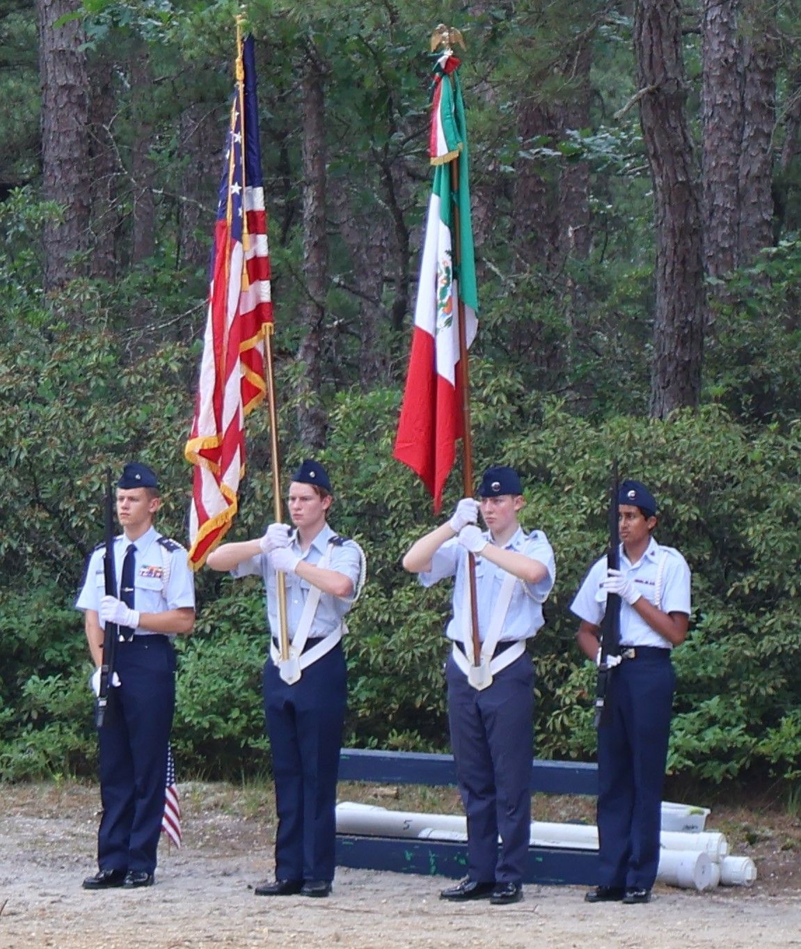 Color guard holding flags in a wooded area; American and Mexican flags are displayed.