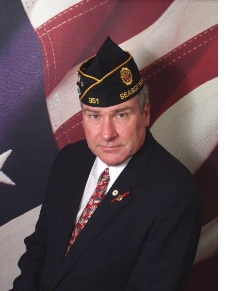 Man wearing glasses and a white cap with a number 346 next to a US flag.