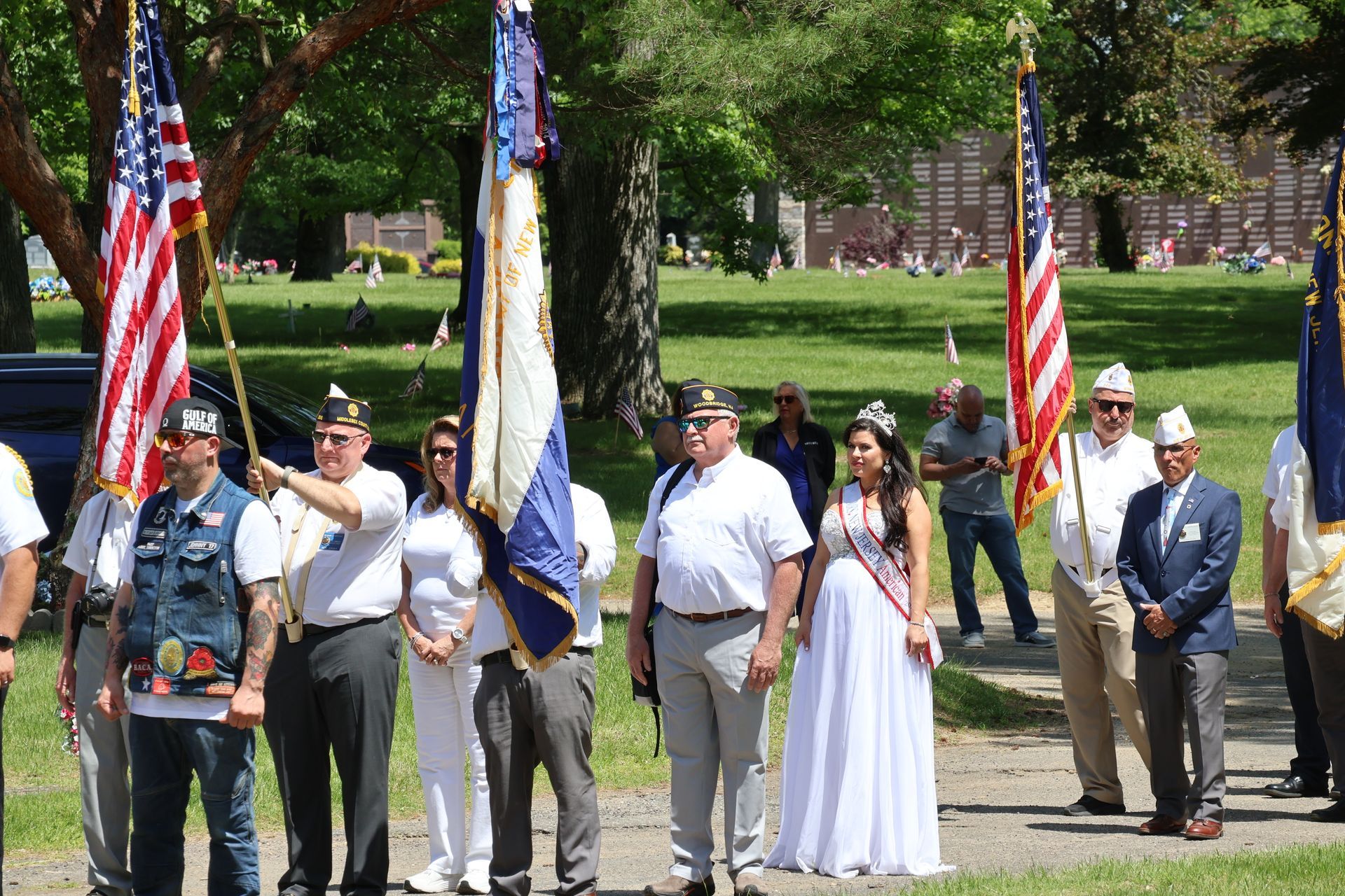 People standing in a park holding American flags during a ceremony