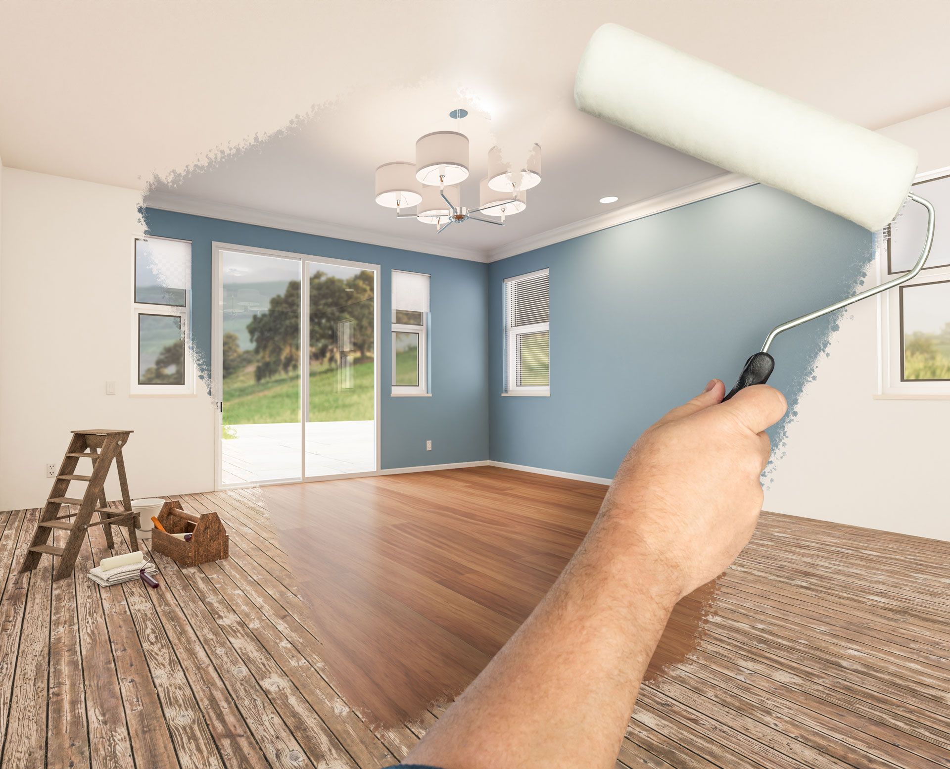 Hand painting a room blue with a roller. Room has windows, hardwood floor, and a stepladder.