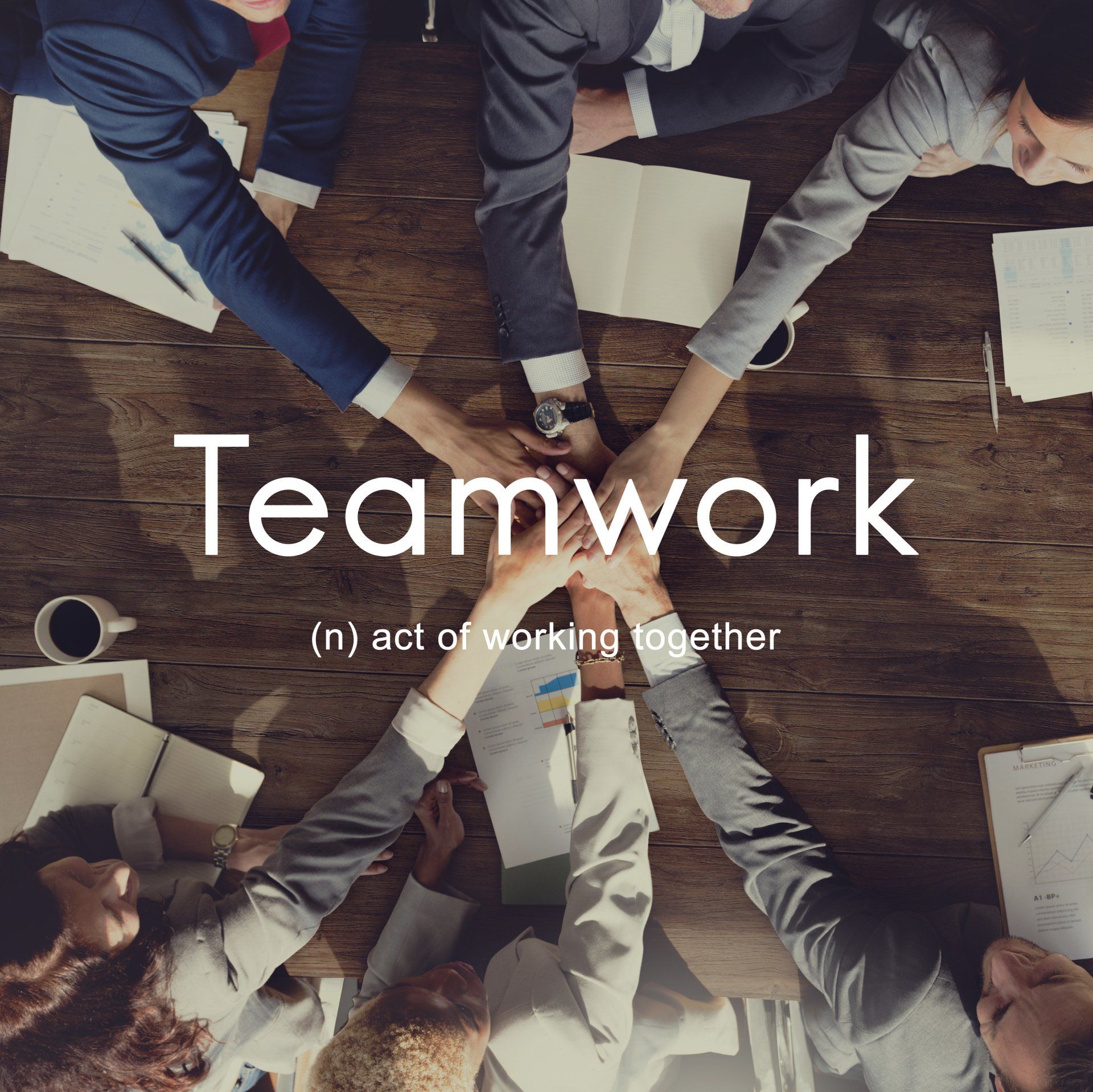 Teamwork text over image of people placing their hands on top of each others hands
