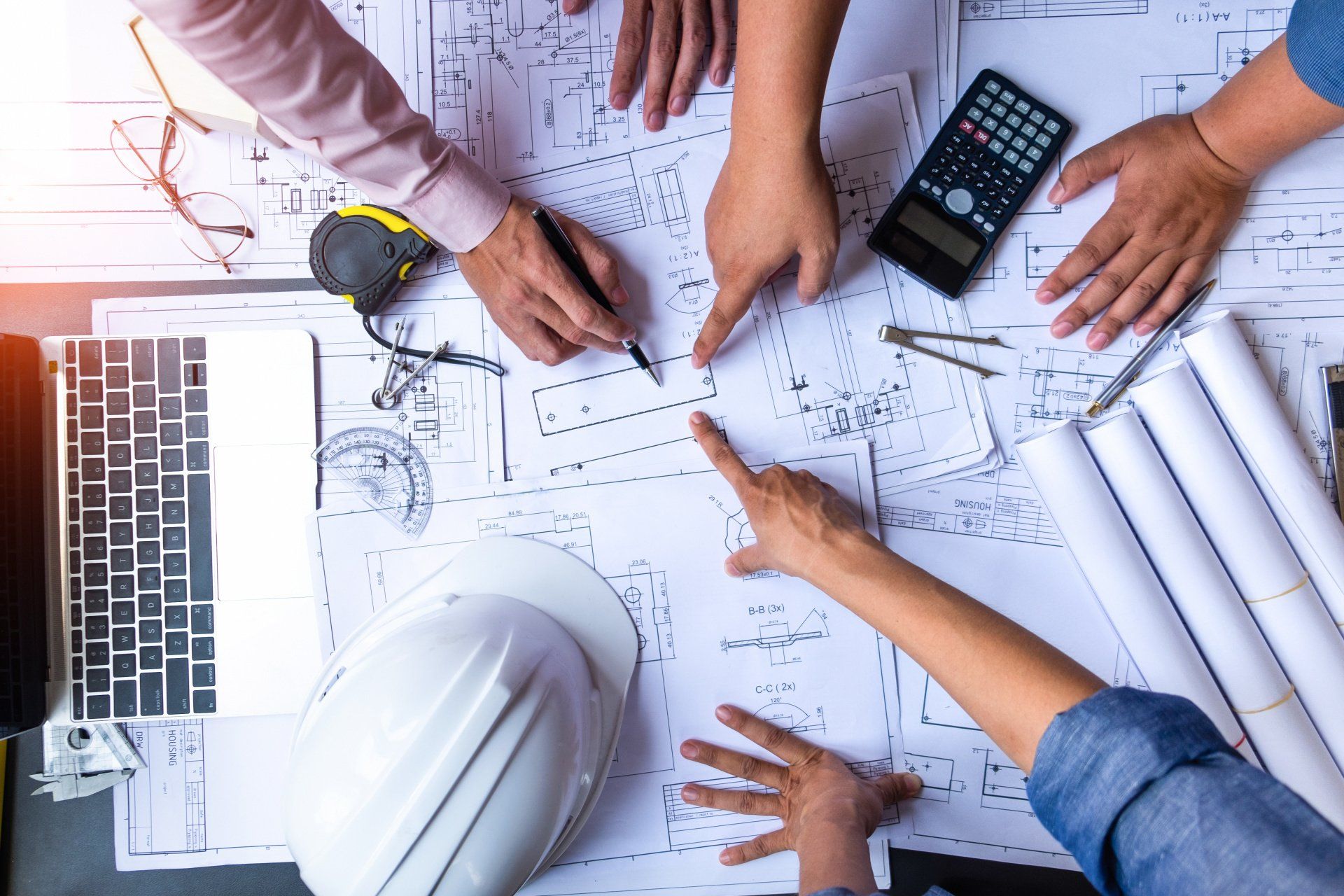 people pointing at construction plans on a table