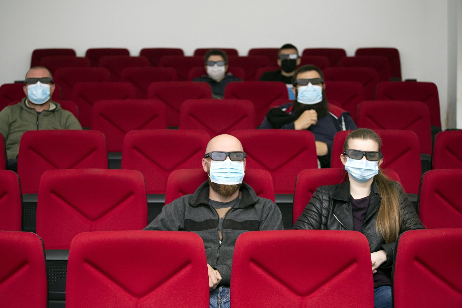 A photograph of a group of people, socially distanced and wearing masks, in a cinema auditorium