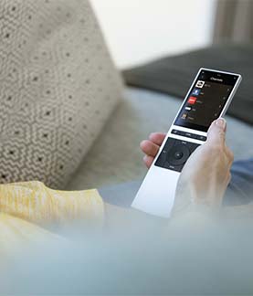 A photograph of someone's hand holding a Control4 Neeo remote control