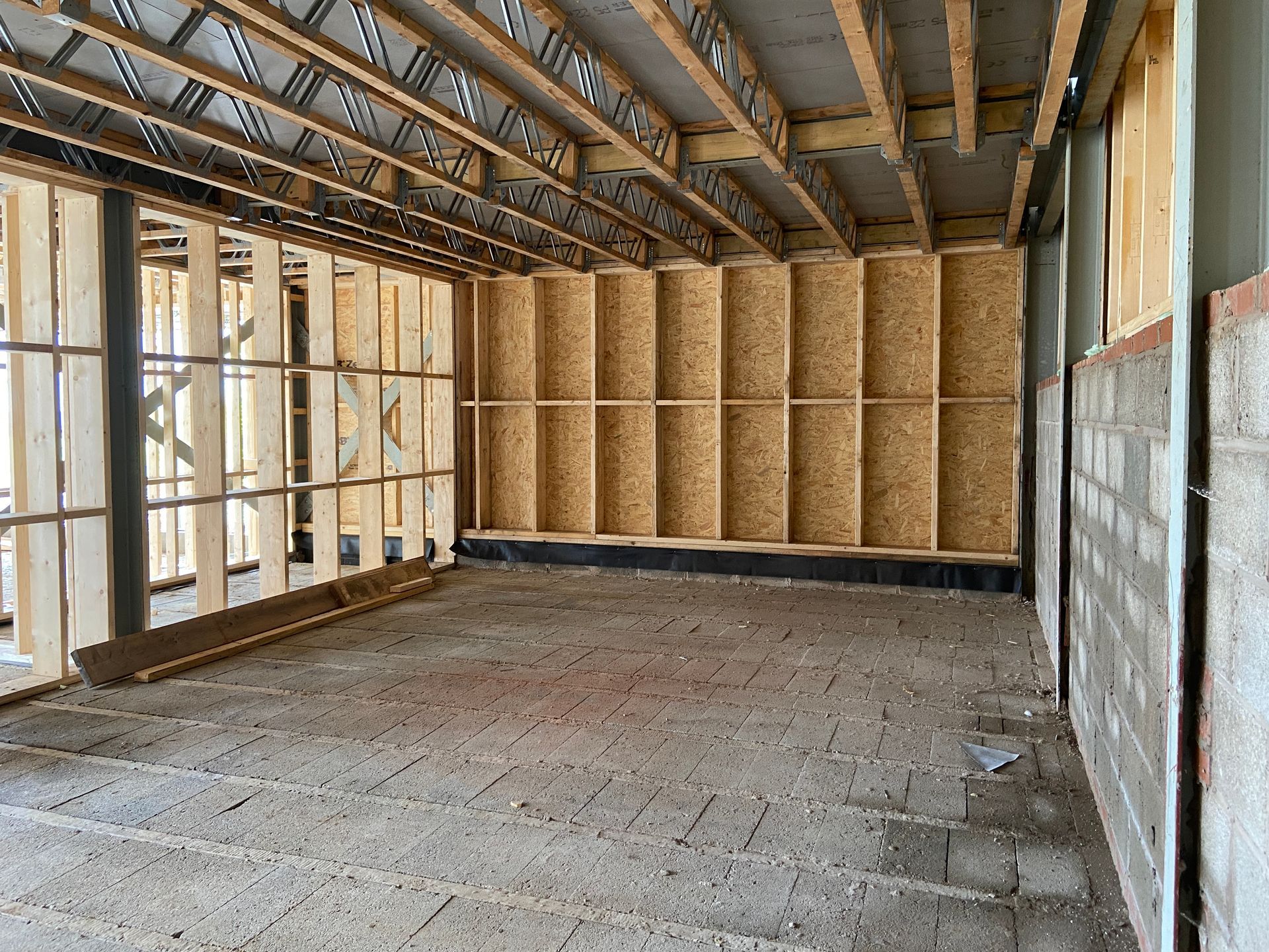 Interior of a building under construction. Wooden framework, concrete floor, and block walls are visible.