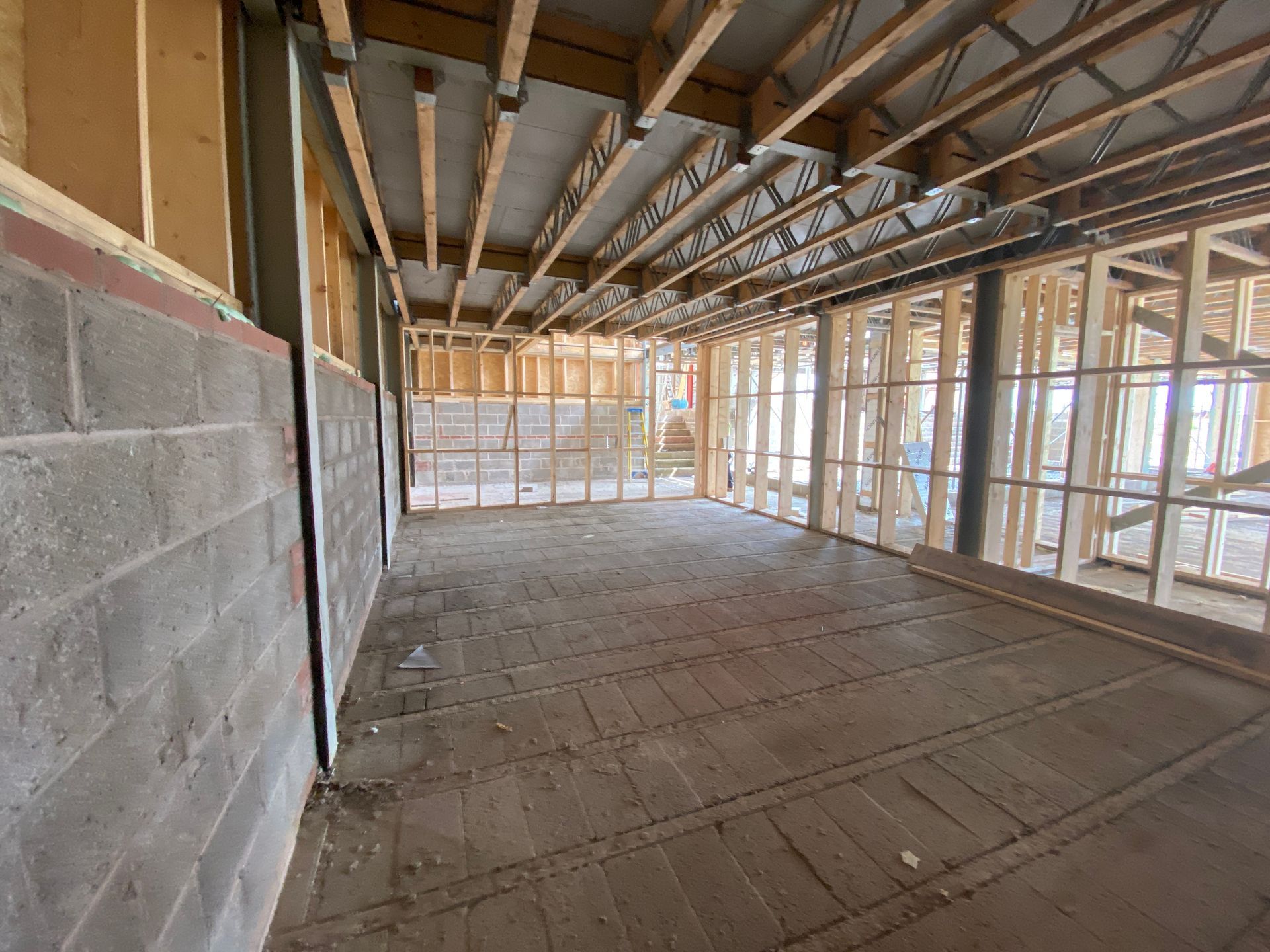 Interior of a room under construction, with exposed wooden beams, studs, and concrete block walls.