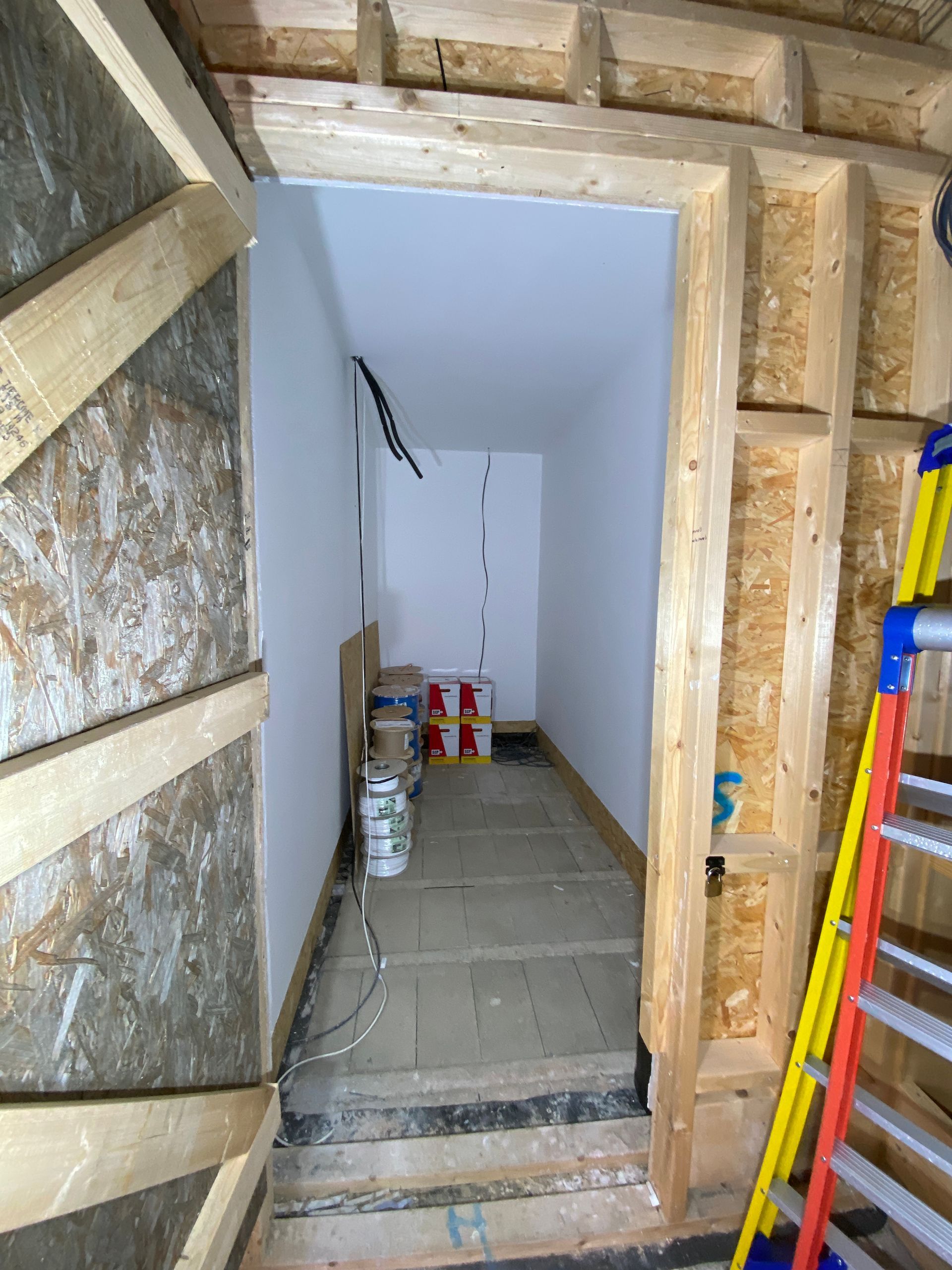 Interior doorway under construction; wood frame, white walls, storage area visible.
