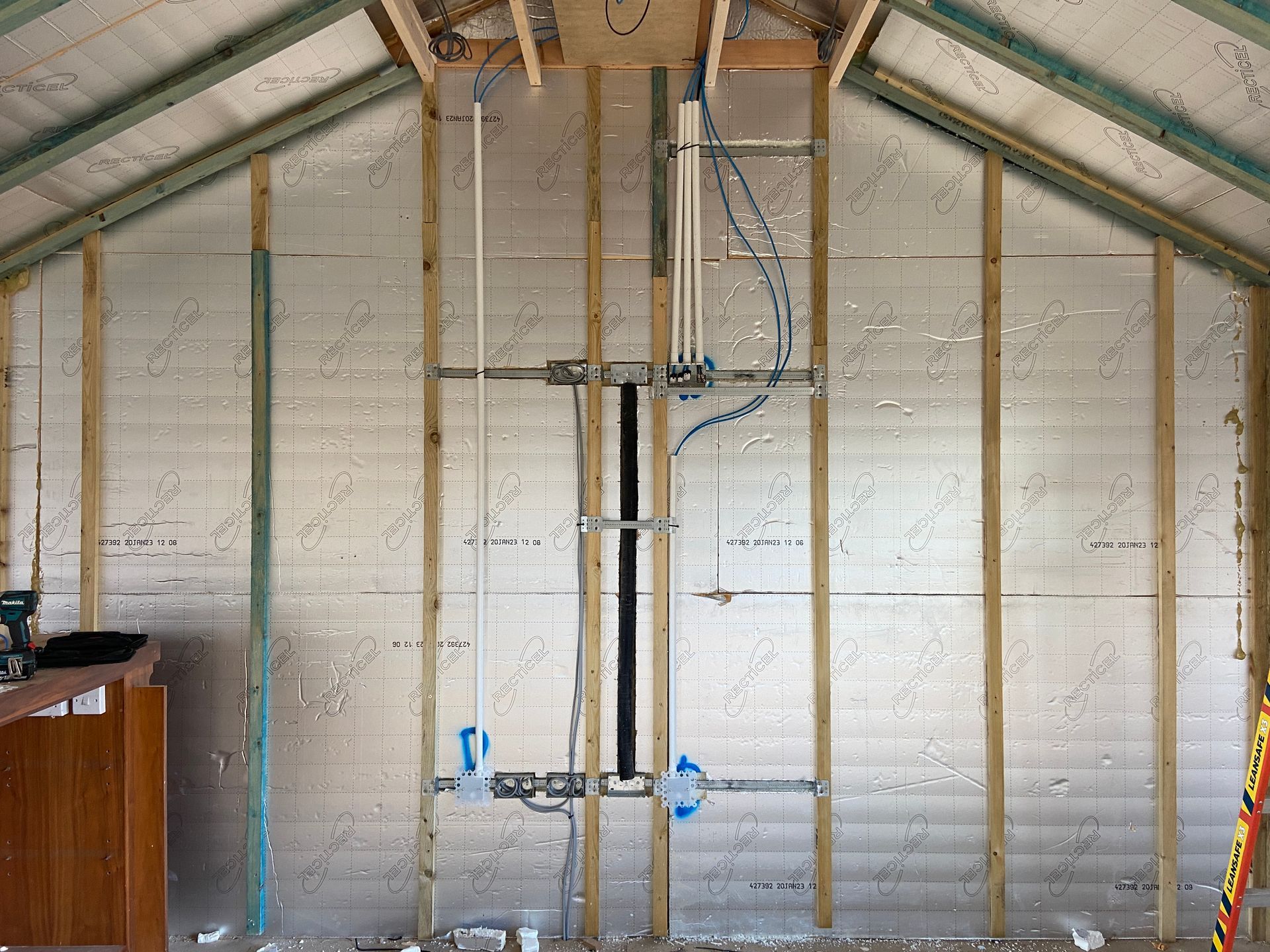 Photo of a TV Point back box behind location of future TV. A conduit to connect from behind TV to a future media cabinet that will be located below the TV. Addition of data points to the media cablnet. 