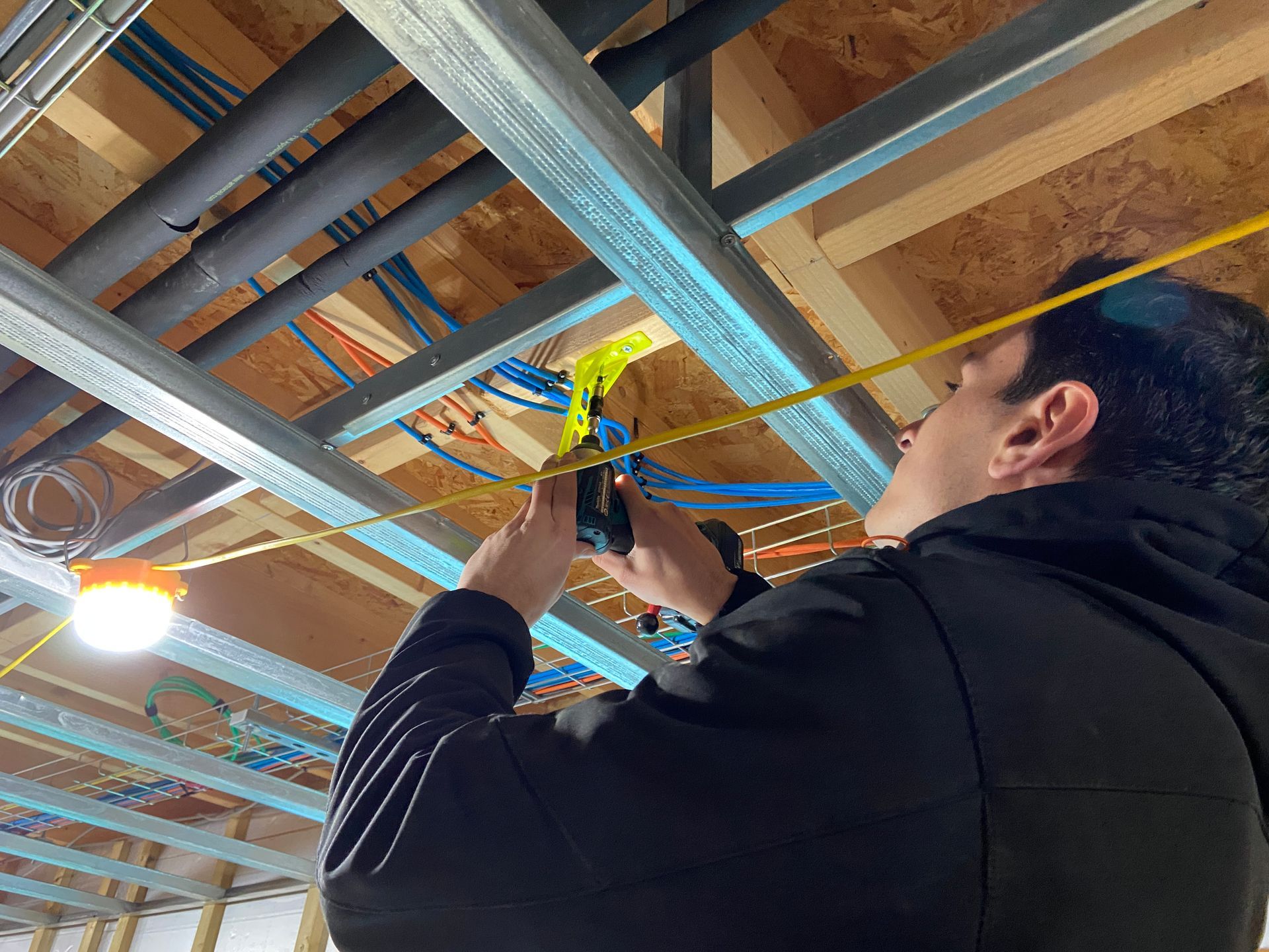 Photo of someone Fixing a cable in place a cable in ceiling void, using a Cableboss mount, for a motion sensor that will be connected to cable during 3rd fix after ceiling has been plastered