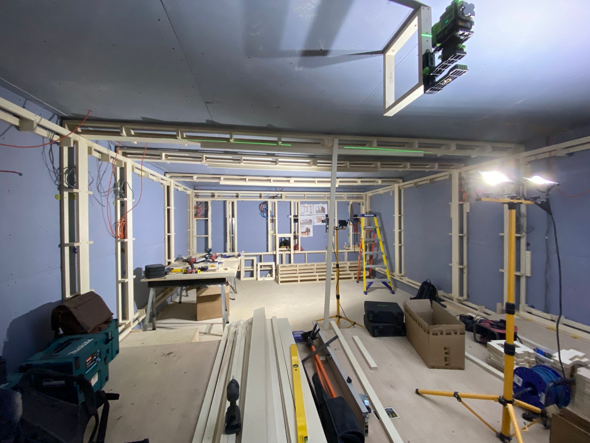 Construction site: wooden framing for interior walls; tools and materials scattered throughout the room.