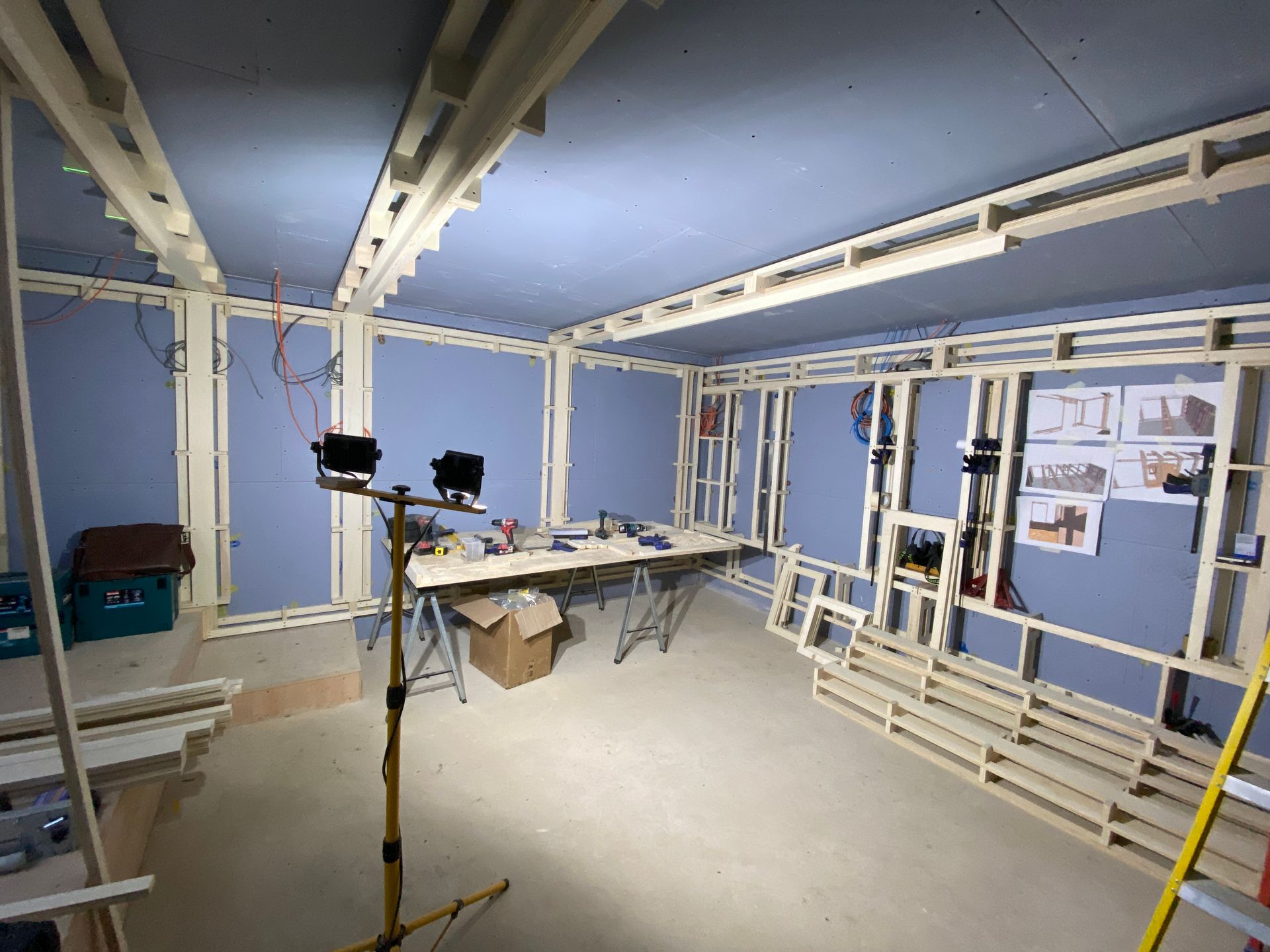 Interior construction site with wooden framing, blue insulation boards, and work tools.